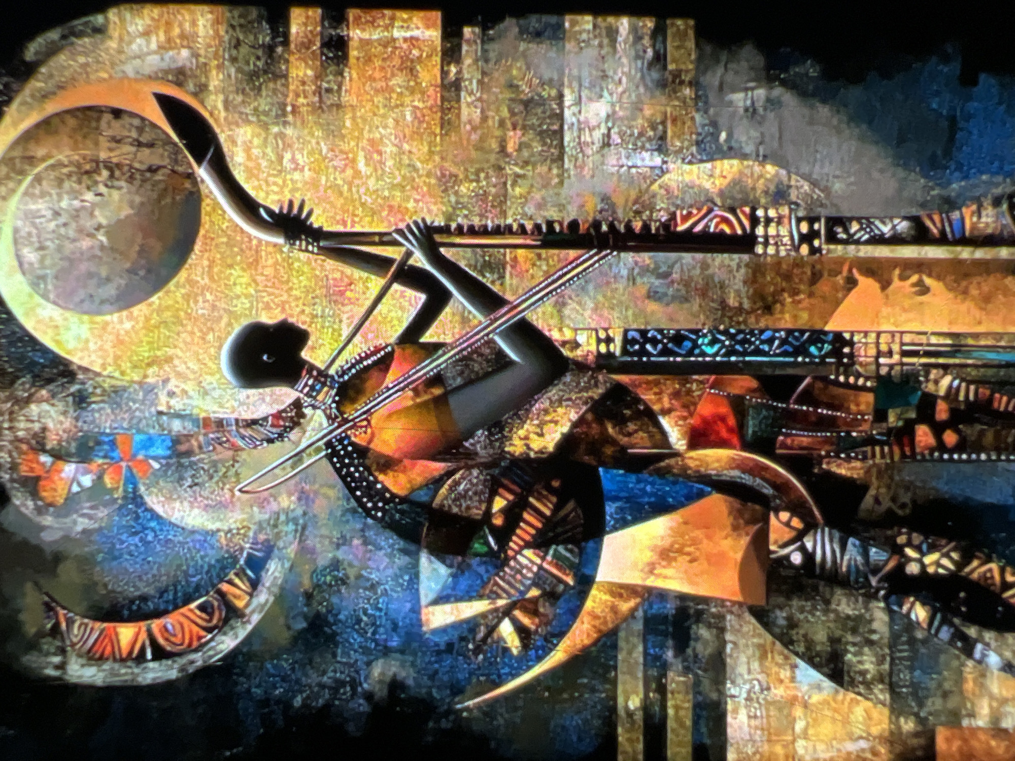The image is a close-up, angled, high-quality, colorful, abstract painting that appears to depict a person with dark skin in profile, holding a musical instrument that resembles a horn or flute. The figure is adorned in richly patterned clothing with geometric designs and beads. The background is a vibrant mosaic of colors, including oranges, yellows, blues, and blacks, with circular and crescent shapes. The style is reminiscent of traditional African art, with bold lines and textured patterns.
The painting does not depict any specific location within the city of Lagos, Nigeria.