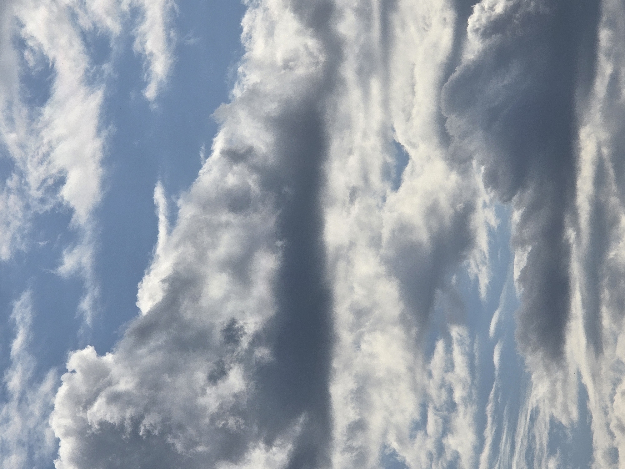 The image shows a close-up view of a cloudy sky. The clouds are a mix of white and dark gray, indicating varying levels of density and possibly impending rain. The sky is a pale blue, peeking through the gaps in the cloud cover. The overall impression is one of dynamic weather.
Based on the provided information that the image is located in the city of Vilnius, Lithuania, this is a typical depiction of the sky over the city. The specific location within Vilnius cannot be determined from the image itself, as it only shows the sky. No people, subjects, objects, actions, or interactions are visible in the image.