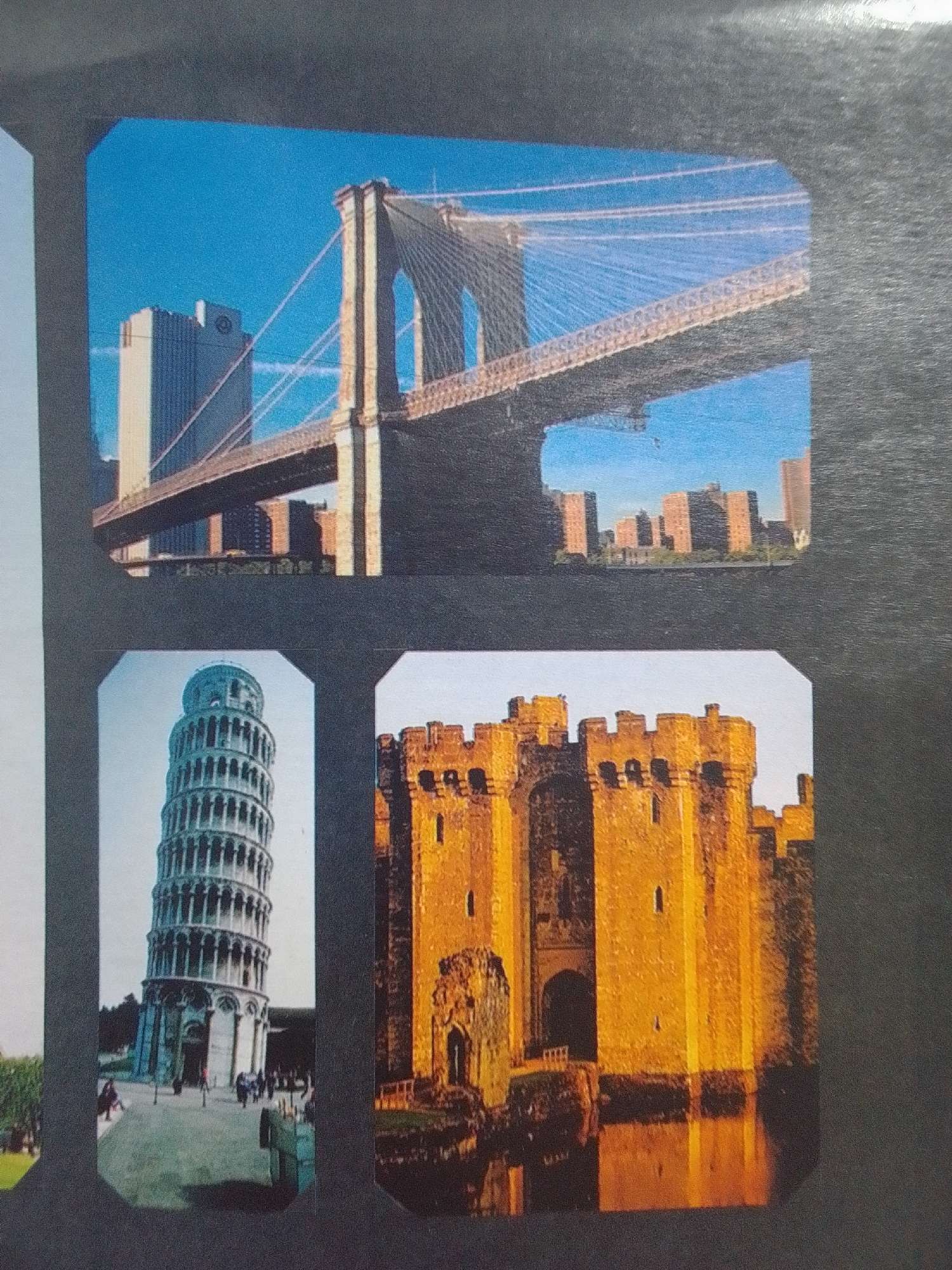 This is a photograph of a collage featuring three iconic landmarks. The top image shows the Brooklyn Bridge in New York City, with the Manhattan skyline in the background. The bottom left image depicts the Leaning Tower of Pisa in Italy. The bottom right image displays a medieval castle, possibly in Europe, with a moat surrounding it. The photographs are set against a dark, textured background, likely a scrapbook or photo album page. There are no elements in the image that indicate the city of La Tagua, Venezuela.
