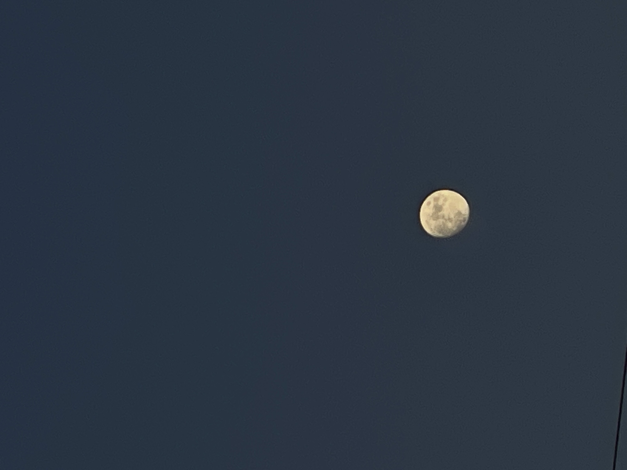 A full moon appears against a dark blue sky. A dark, thin line is visible in the lower right corner of the image, likely a power line. The scene appears to be taken at night. The specific location in Popasne, Ukraine, cannot be determined from the image. There are no people or interactions visible.