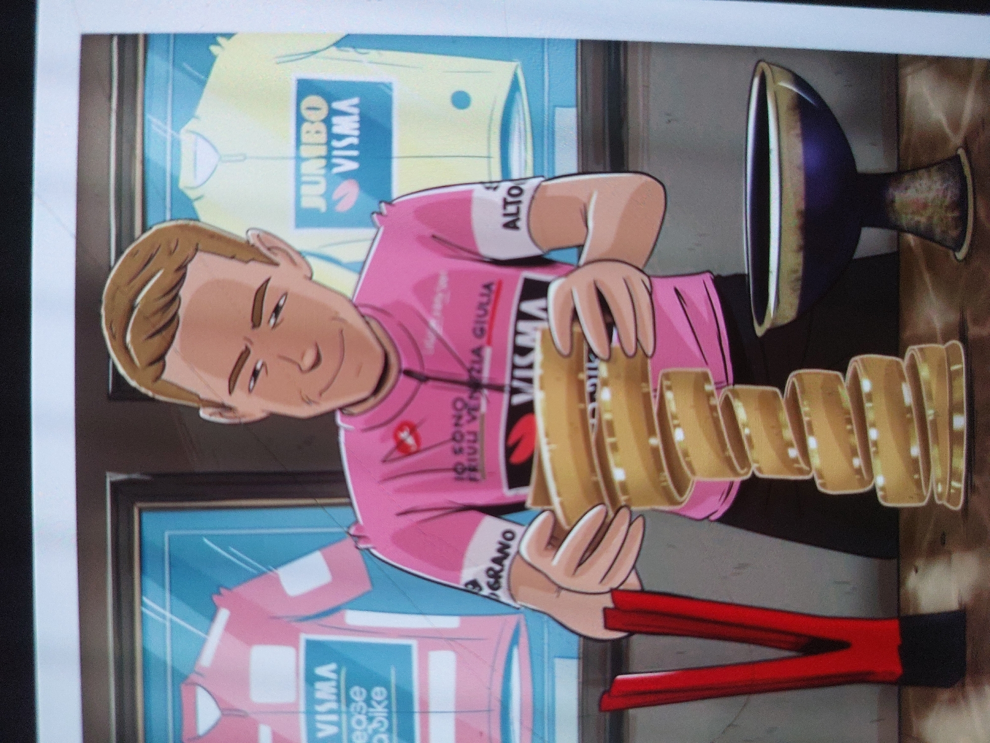 An illustrated image features a cartoon male figure, light-skinned with short brown hair, holding a large golden trophy. He is smiling faintly, looking towards the viewer. The figure wears a pink cycling jersey adorned with various texts, including "VISMA", "IO SONO FRIULI VENEZIA GIULIA" across the chest, and "ALTO" on a white band around his upper left arm. Another partial text "GRANO" is visible on his right arm.
The trophy is ornate, resembling a chalice with a dark blue or purple bowl at the top, and a base composed of stacked, undulating golden rings.
In the background, behind the figure, are two framed cycling jerseys displayed as if in a glass case or window. The upper jersey is light yellow with "JUMBO VISMA" written in blue. The lower jersey is pink, also featuring "JUMBO VISMA" in blue, and additional text that reads "Lease a bike". The overall scene suggests a celebratory moment, possibly depicting a cyclist who has won a major race, given the design of the trophy, which closely resembles the "Trofeo Senza Fine" of the Giro d'Italia, and the pink leader's jersey worn by the character and displayed in the background. The background jerseys indicate an affiliation with the Jumbo-Visma cycling team.