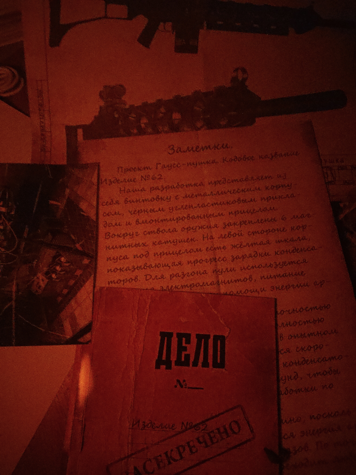 The image shows a collection of documents and sketches related to a project, likely of a classified nature. The prominent document in the foreground is titled "ДЕЛО" (Case) with a number space left blank. Below it is a stamp stating "АСЕКРЕЧЕНО" (Declassified). Another document mentions "Проект Гаусс-пушка" (Project Gauss Rifle) with the designation "Изделие №62" (Article No. 62), suggesting it is a research or development project related to a type of electromagnetic rifle. The text describes the rifle's components: a metal body, black carbon-plastic stock, integrated sight, and six magnetic coils around the barrel. There is a description of a yellow scale displaying the charging progress of capacitors, as well as the power source, describing it as the electromagnetic drive receiving power via energy source. In the background are outlines and diagrams of what appear to be the rifle itself, adding to the overall technical and secret-document theme. The warm red lighting gives the image a sense of secrecy and antiquity.