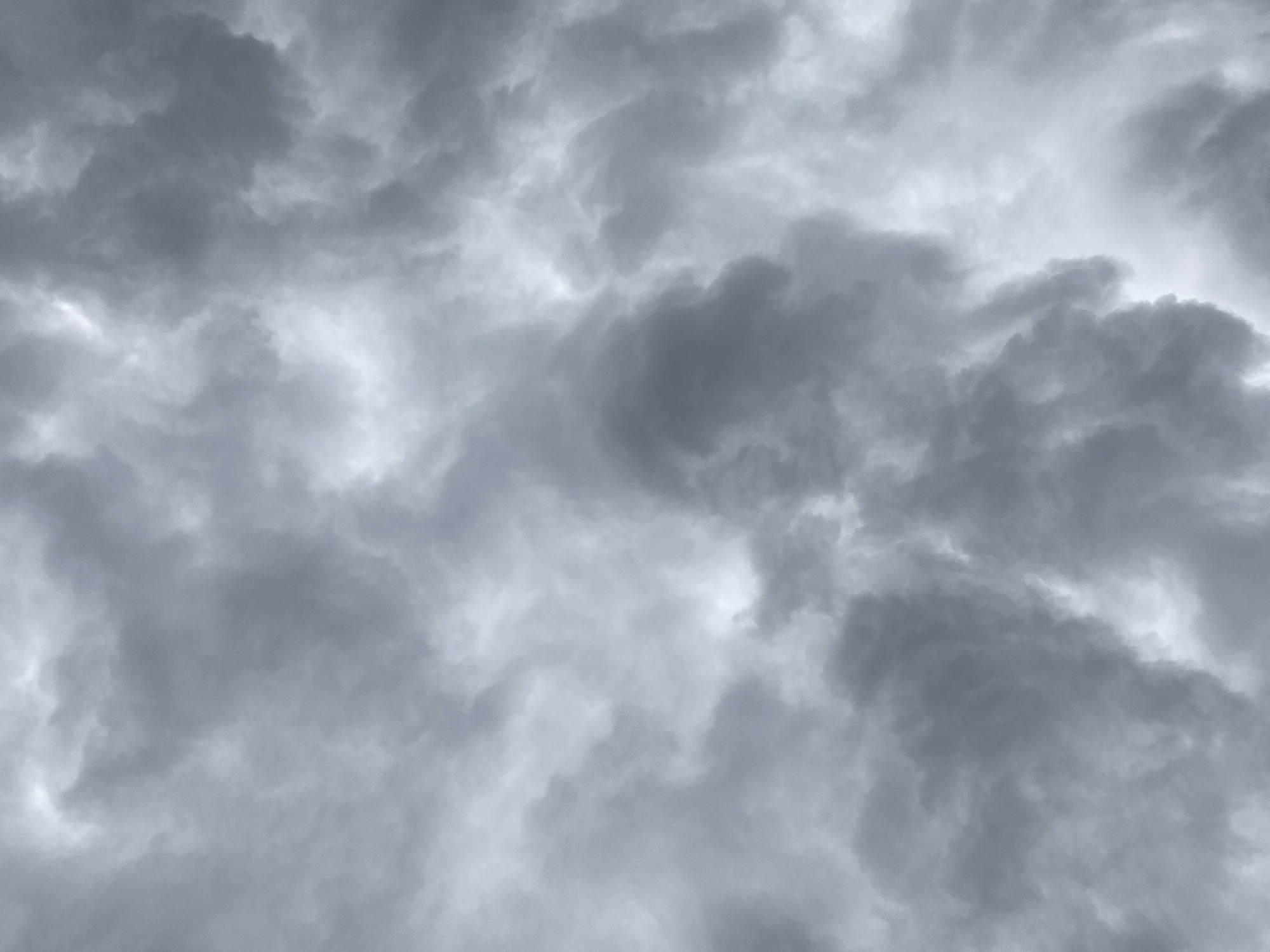 The image shows a sky filled with dark, ominous clouds. The clouds are predominantly gray and white, with varying shades indicating different thicknesses and densities. The overall scene conveys a sense of impending bad weather, possibly a storm. There is no indication of the location being in the city of Maigizo, Nigeria, or any other human presence or activity in the image. It is solely a depiction of a cloudy sky.
