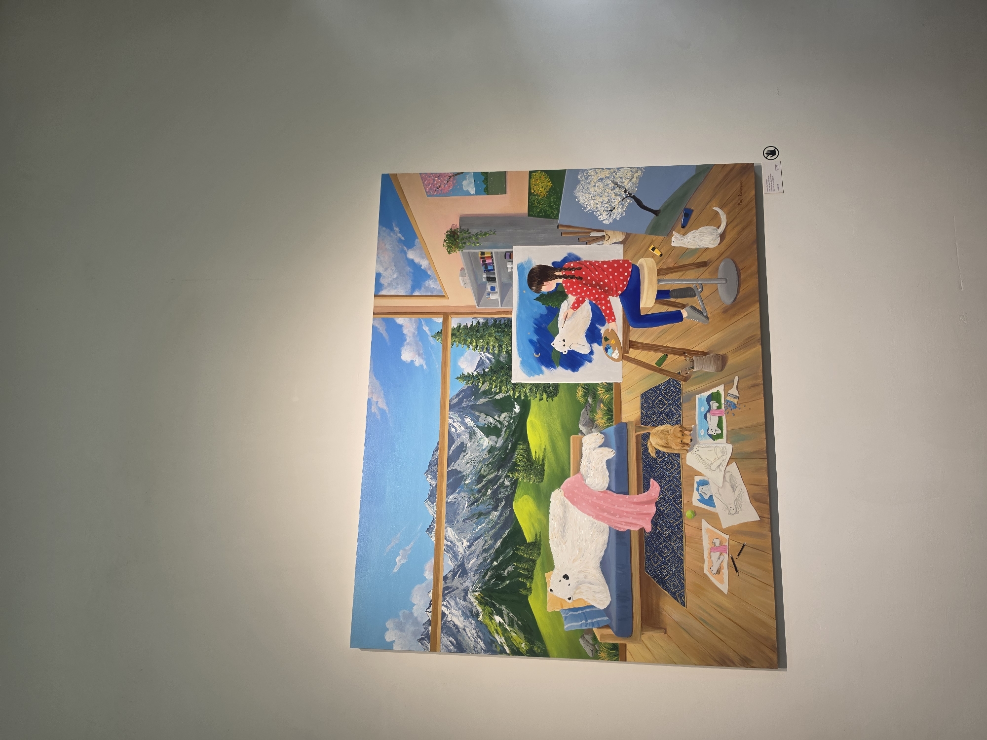 A rectangular painting is mounted on a white wall. The painting depicts a scene within a room, featuring an artist at an easel painting a white dog. Behind the artist is a window with a mountain landscape view. The floor is wooden, and various sketches of dogs are scattered around the room. A white cat is present near the easel. The location is Bangkok, Thailand.