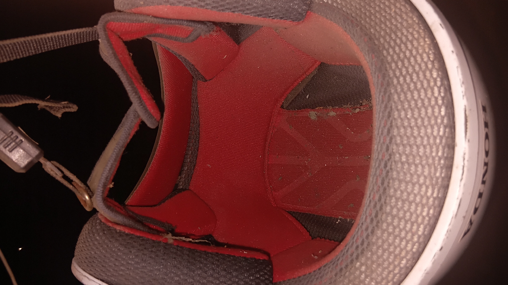 The image shows the interior of a white Honda motorcycle helmet. The lining is red and gray, and appears to be somewhat dirty. The helmet straps are visible at the top. The brand name "HONDA" is visible on the outside edge of the helmet. The scene is dark, suggesting it is indoors or nighttime. There is no indication of the location in Prabumulih, Indonesia.