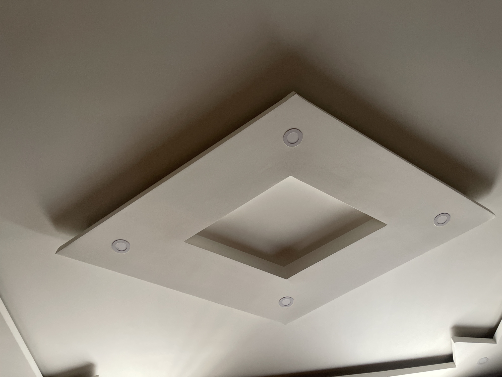 The image shows a ceiling with a square recessed design. Four circular recessed lights are placed on the perimeter of the square design. The ceiling is white or off-white. The overall scene suggests an interior space. It's impossible to determine the location in Tbilisi, Georgia or any people, actions, interactions, or additional details about the environment from this image.