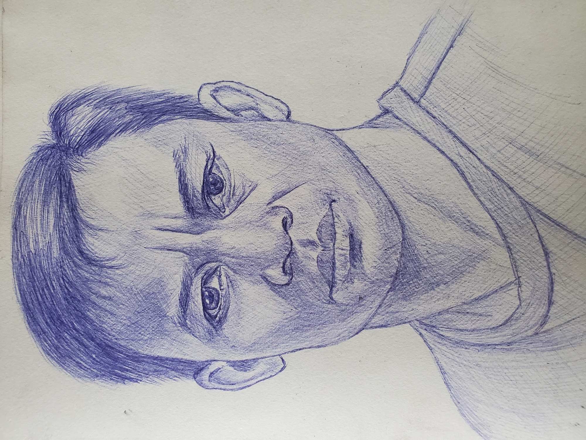 A portrait, rendered entirely in blue ballpoint pen, depicts an individual from the chest up. The drawing is characterized by extensive use of hatching and cross-hatching lines to create depth, shadows, and texture across the subject's face, hair, and clothing.
The subject, who appears to be male, has short, textured hair, deep-set eyes with an intense and direct gaze, a prominent nose, and full, slightly parted lips. A subtly furrowed brow contributes to a serious or contemplative expression. Both ears are visible, and the outline of a collared garment is suggested on the right side of the frame. The artwork is presented on plain, light-toned paper, which shows minimal texture. The entire image is oriented such that the subject's head is tilted to the right, relative to a standard upright portrait view. No visible text is present within the drawing.