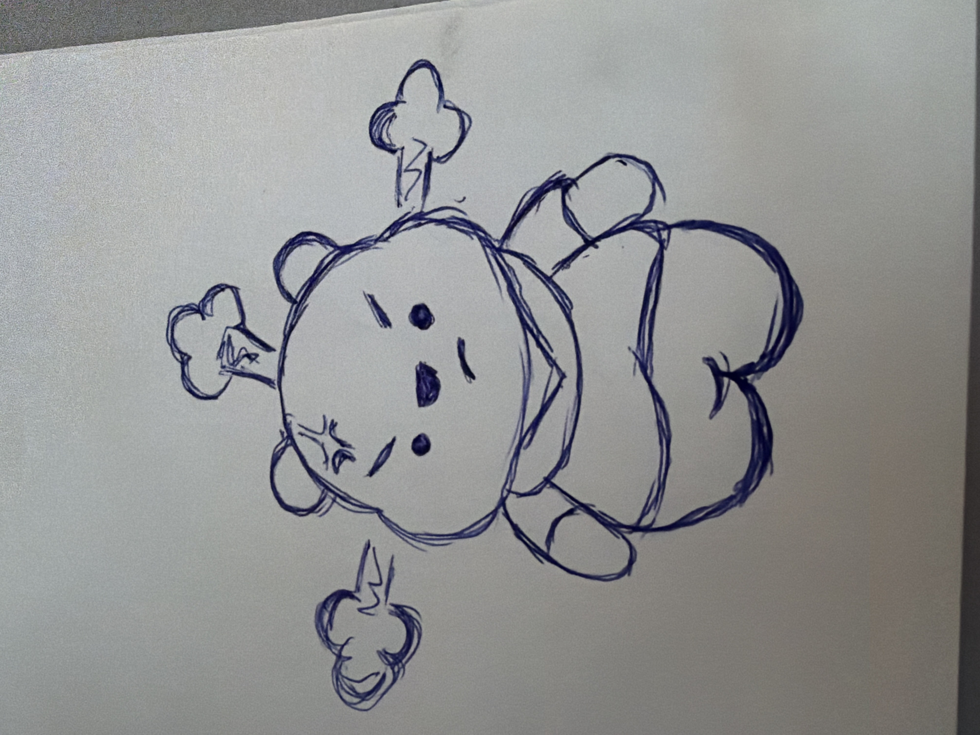 The image is a close-up, eye-level, high-angle shot of a blue ink sketch on a white textured surface, possibly paper. The sketch depicts a cartoonish, plump bear character with an angry expression. The bear has its eyes narrowed, eyebrows furrowed, and a downturned mouth. Two puffs of stylized smoke are shown emanating from its ears, and another puff is above its head, suggesting it is extremely upset or "steaming." The bear is wearing a simple outfit, possibly a t-shirt with a rounded neckline and a belly band. The sketch is rendered in a loose, sketchy style with visible pen strokes. There is no indication of the location of Rostov-on-Don, Russia, or any urban environment within the image. The focus is solely on the drawing itself.