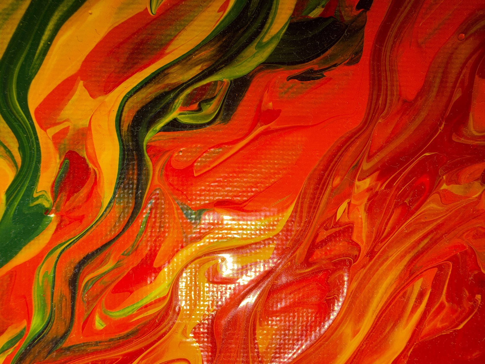 This is an abstract image of acrylic paint on canvas. The colors are predominantly red, orange, yellow, and green, swirled and blended together in organic, flowing patterns. The texture of the canvas is visible in some areas, creating a slightly raised, granular effect. There is a glossy sheen to the paint in places, suggesting a wet or semi-wet application. The image is a close-up view of the paint, with no discernible objects, people, or environment from a city like Nha Trang.