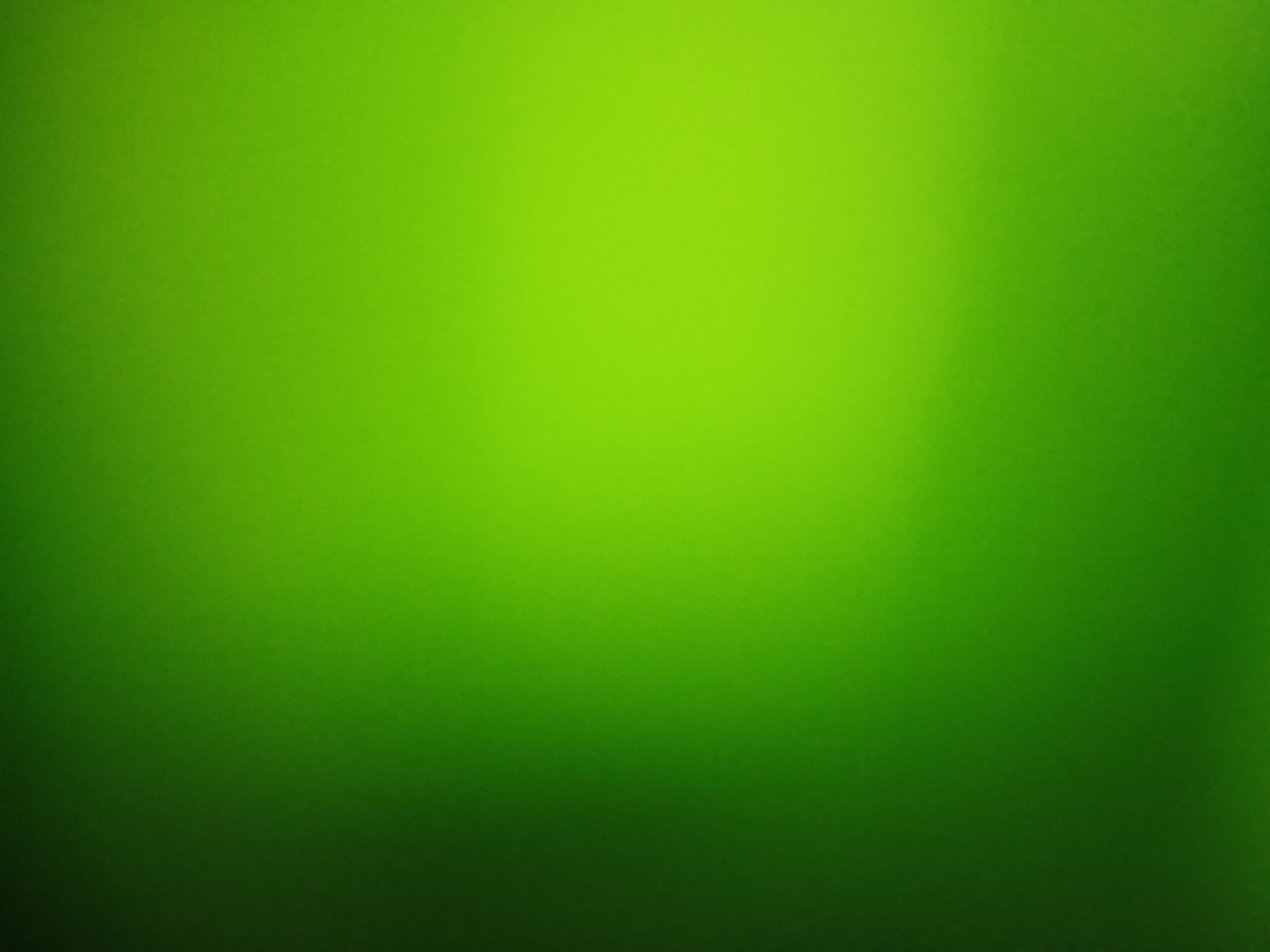 The image is an abstract, unfocused shot of a gradient of green. There is a dark green shadow on the left side of the image, which lightens to a bright lime green on the right. The background is smooth and untextured, suggesting a digitally generated image or a very smooth surface. There are no discernible objects, people, or actions within the frame. The image is not specific to any location in Sekarputih, Indonesia, or any other geographical area.