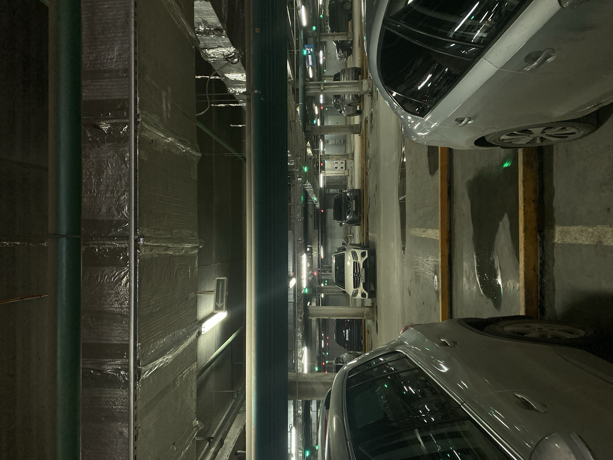 The image depicts the interior of an underground parking garage. Several cars are visible, parked in marked spaces. Overhead, there are fluorescent lights and ductwork. The structure appears to be modern. It cannot be confirmed that this image is from Yekaterinburg, Russia.