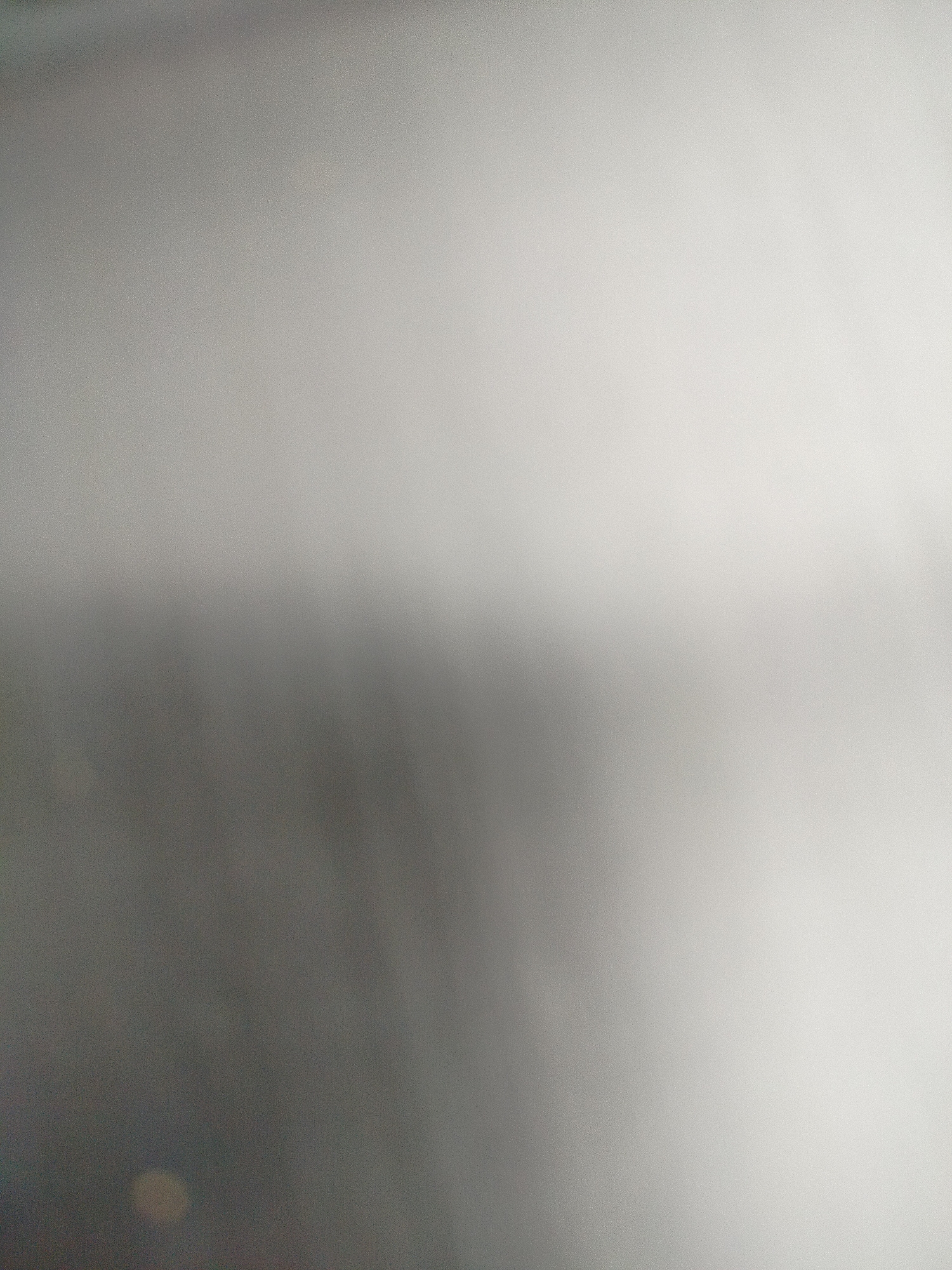 The image appears to be an out-of-focus photograph, potentially taken indoors. The overall color palette is grayscale, with varying shades of gray ranging from dark to light. There are no identifiable subjects, objects, people, actions, or interactions visible. Given the blurriness and lack of distinct features, it is impossible to determine if the image was taken in Yerevan, Armenia, or any other specific location.