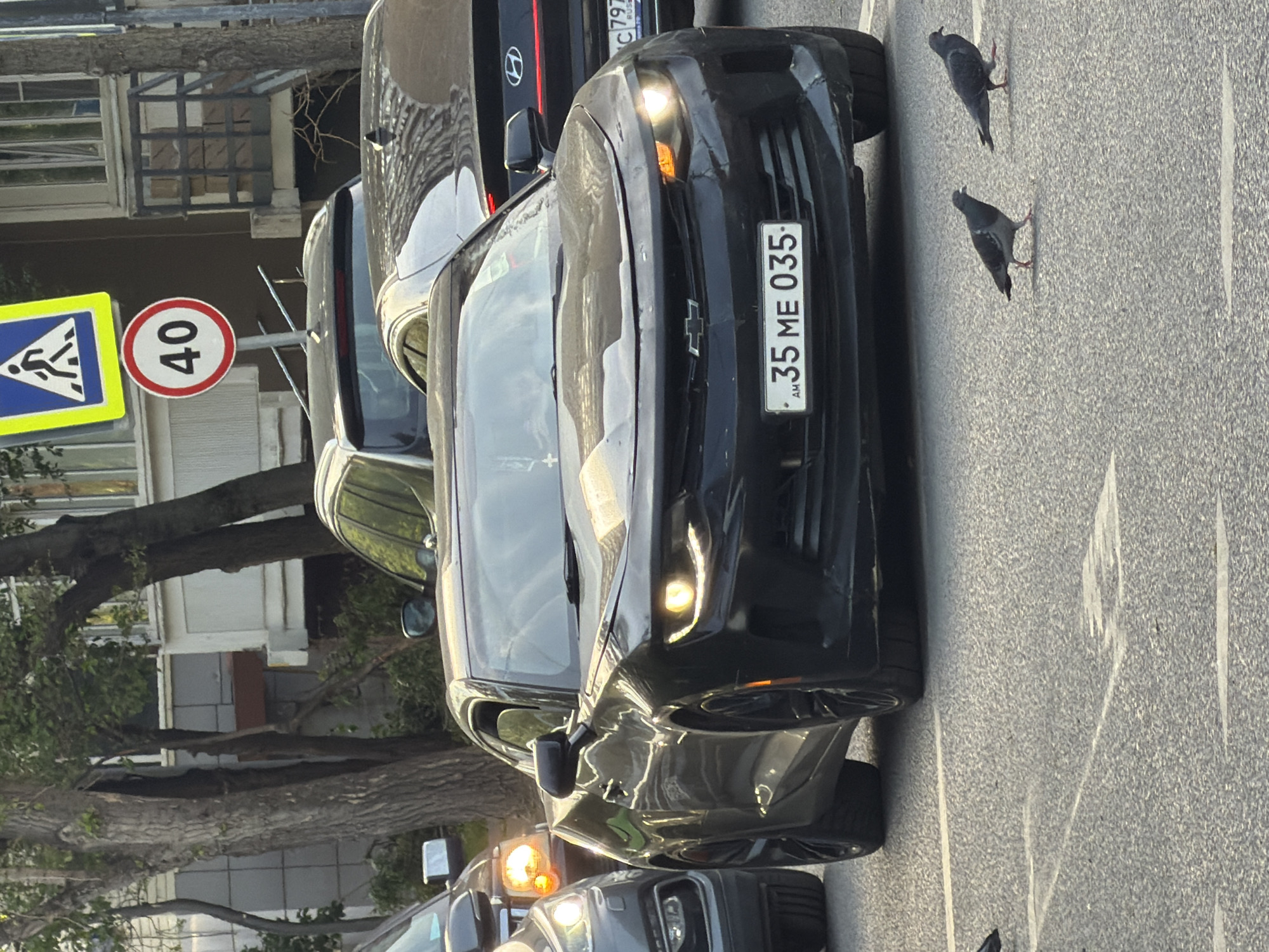 The image shows a black Chevrolet Camaro parked on a street. The car's license plate reads "35 ME 035" and has the country code "AM," indicating it is from Armenia. The image also contains a pedestrian crossing sign and a speed limit sign indicating 40 km/h. Based on the license plate of the car and the pedestrian crossing, it is possible the image was not taken in Moscow, Russia.