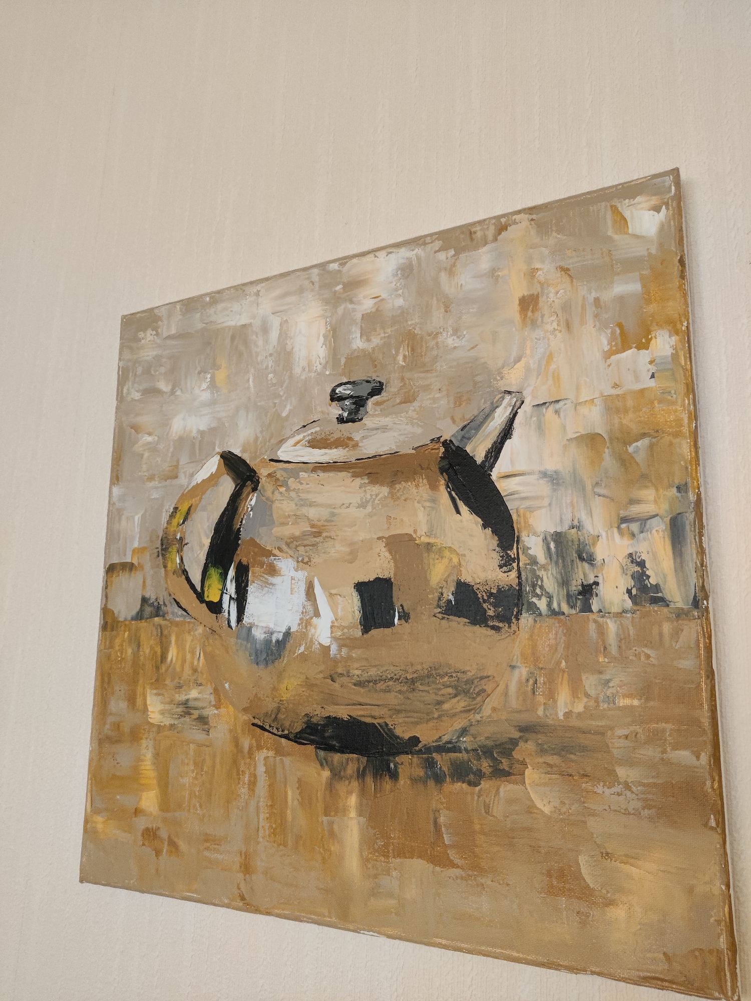 An abstract painting of a teapot is mounted on a textured, cream-colored wall. The painting is rendered in a palette of gold, brown, white, and black, with thick, visible brushstrokes. The teapot itself is centrally located, with its handle and spout clearly defined. The background is a blend of these colors, creating a textured and somewhat abstract environment. The image is taken from a slightly elevated angle, looking down and across the painting. The location is not specified within the image itself, and therefore cannot be determined to be in Winterswijk, Netherlands or any other city.
