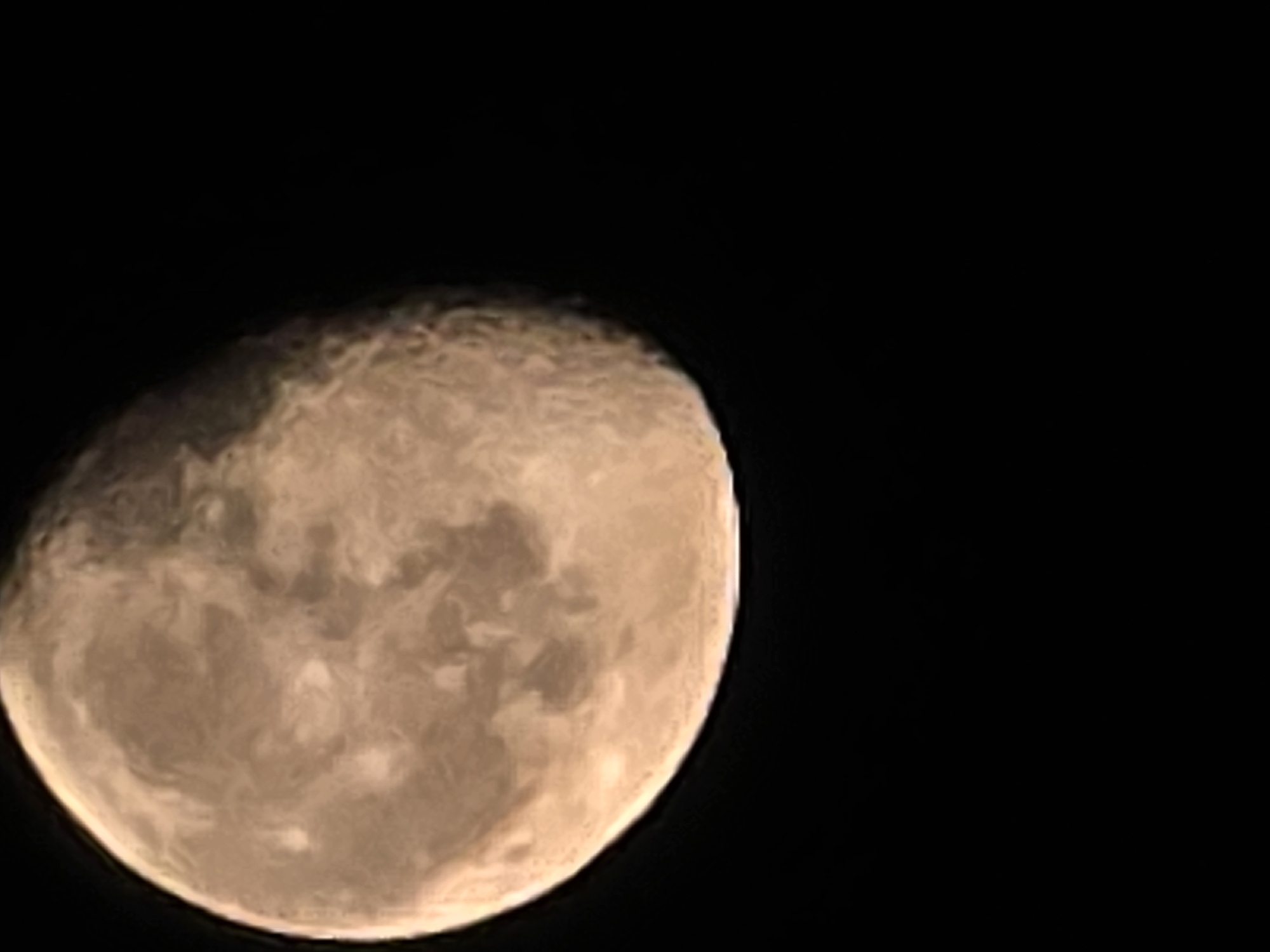 The image shows a close-up view of the moon against a black background. The moon is illuminated from the left, with its surface exhibiting craters and varying shades of gray and tan, suggesting a waxing or waning phase. The bottom portion of the image is mostly black, indicating the surrounding night sky. There is no identifiable city, location in Yambol, Bulgaria, or any other people, subjects, or actions depicted in the image.