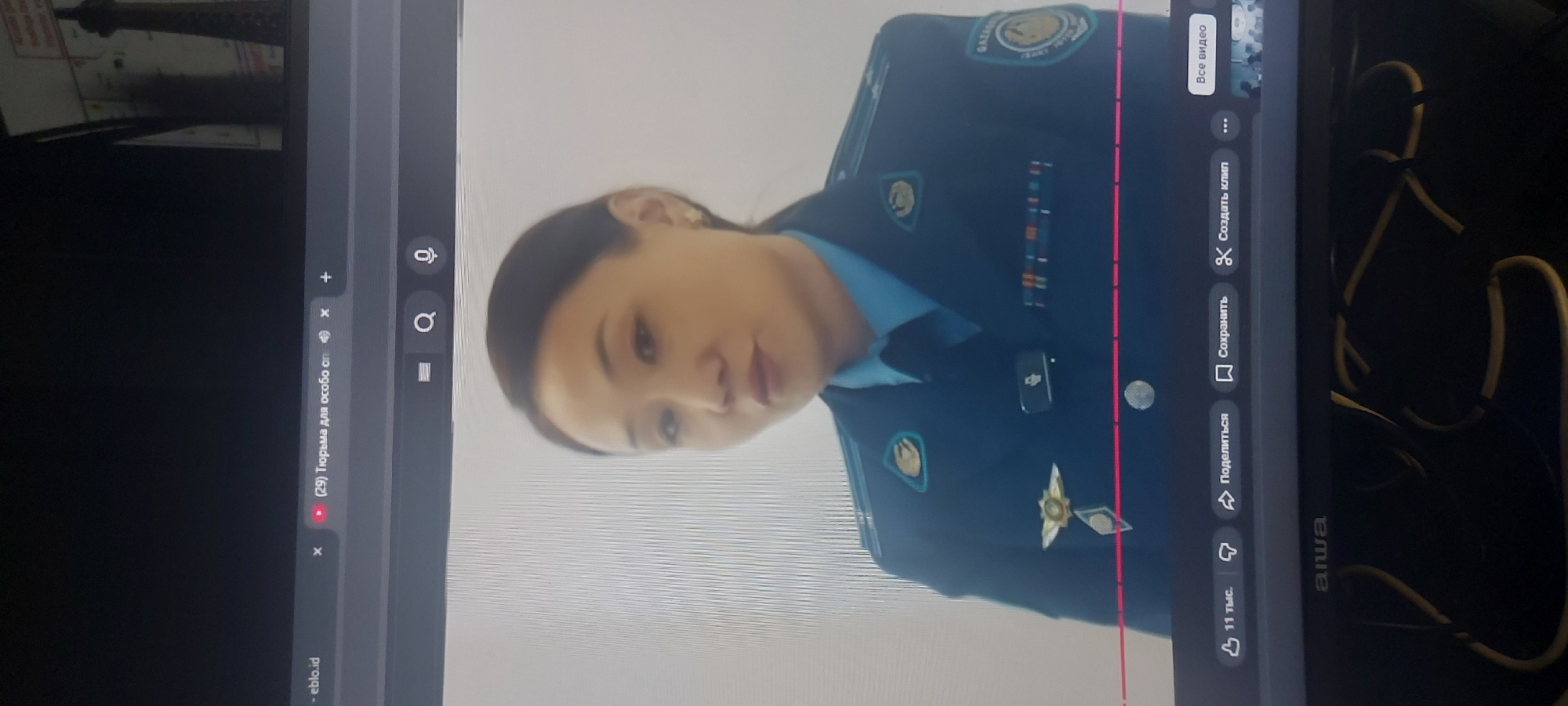 The image shows a computer screen displaying a YouTube video featuring a woman in a blue uniform, likely related to law enforcement or a similar service in Uzbekistan, possibly in the city of Tashkent, given the uniform details and patch. The video is in a browser with the address bar visible, and YouTube controls like "Share," "Save," and "Create Clip" are visible. The screen is an "alwa" brand device. The video has 11,000 likes.