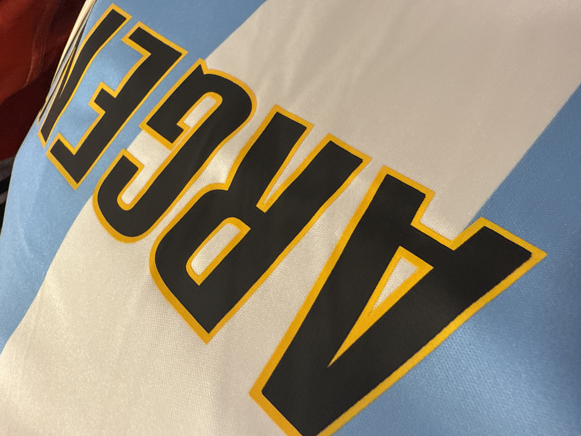 A close-up shot of fabric with the word "ARGE" printed on it, styled in black with yellow bordering. The fabric background features light blue and white stripes. The image lacks identifiable elements to connect it to Dania Beach, Florida.