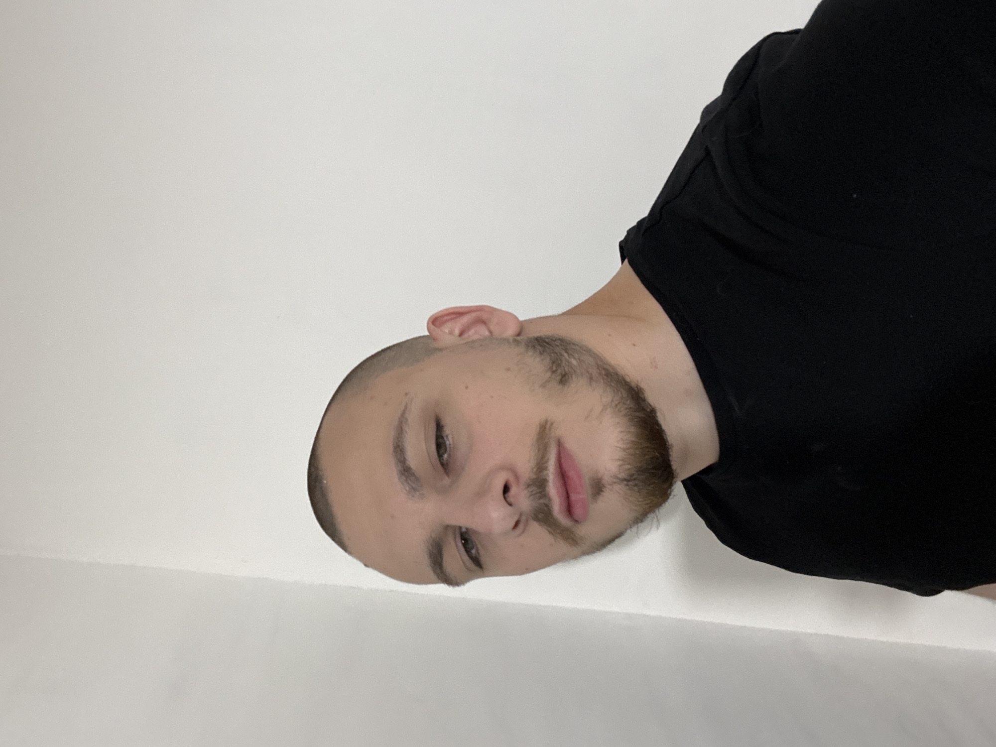 A man with short, light brown hair and a beard is wearing a black t-shirt and looking at the camera. He appears to be standing indoors against a white wall. The location and city of Stara Zagora, Bulgaria cannot be determined from the image alone.