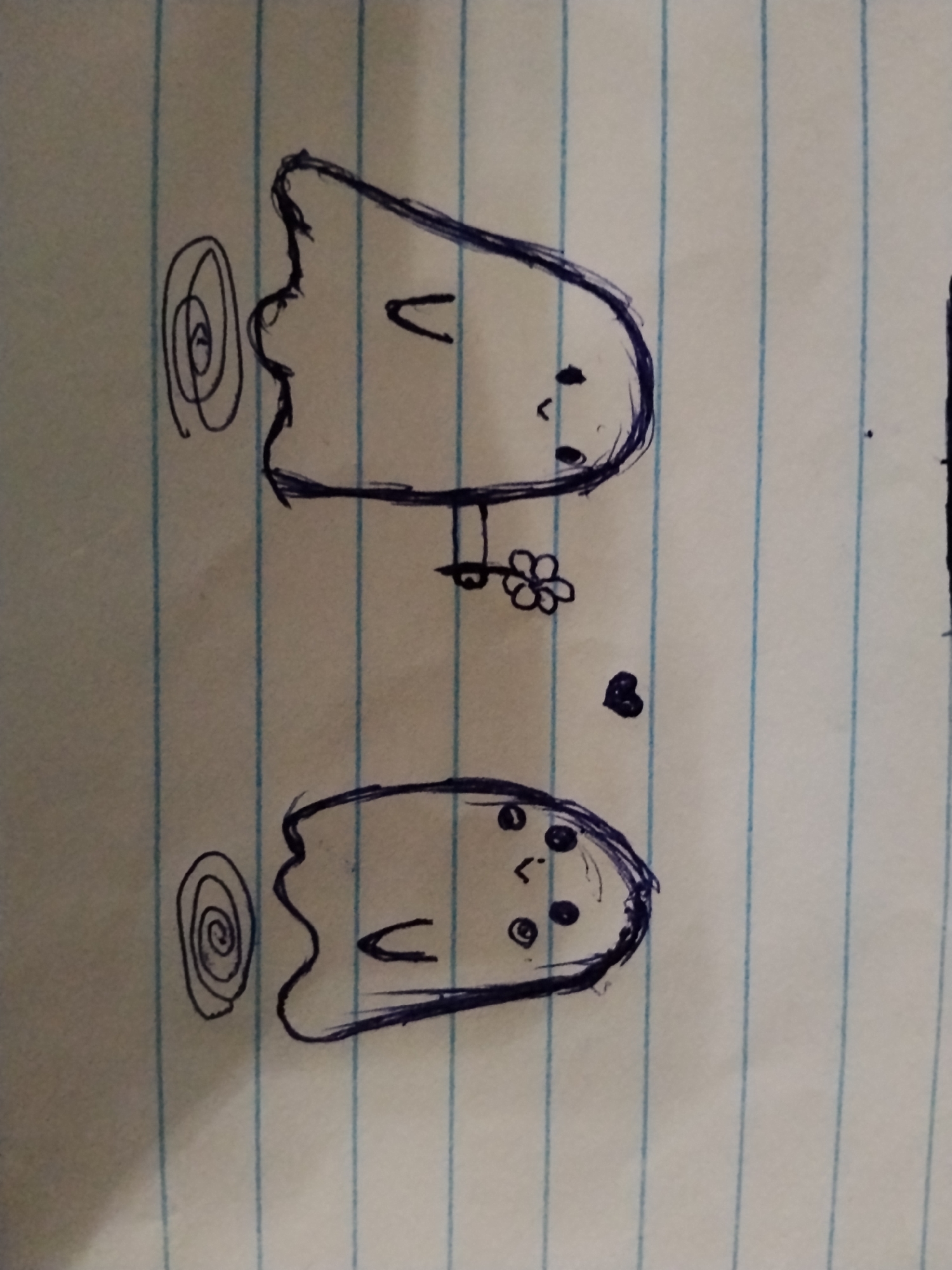 The image displays a hand-drawn illustration on lined paper, featuring two cartoon ghosts. The top ghost has a U-shaped mouth and two dots for eyes, with a swirl to its left. A small, four-petaled flower is drawn near its body, and a small heart is located below the flower. The bottom ghost has a similar U-shaped mouth and multiple dots for eyes. A swirl is drawn to its left. The drawing is done in dark blue ink. The background is a lined notebook page. There are no indications of Bishkek City, Kyrgyzstan, or any other specific location.