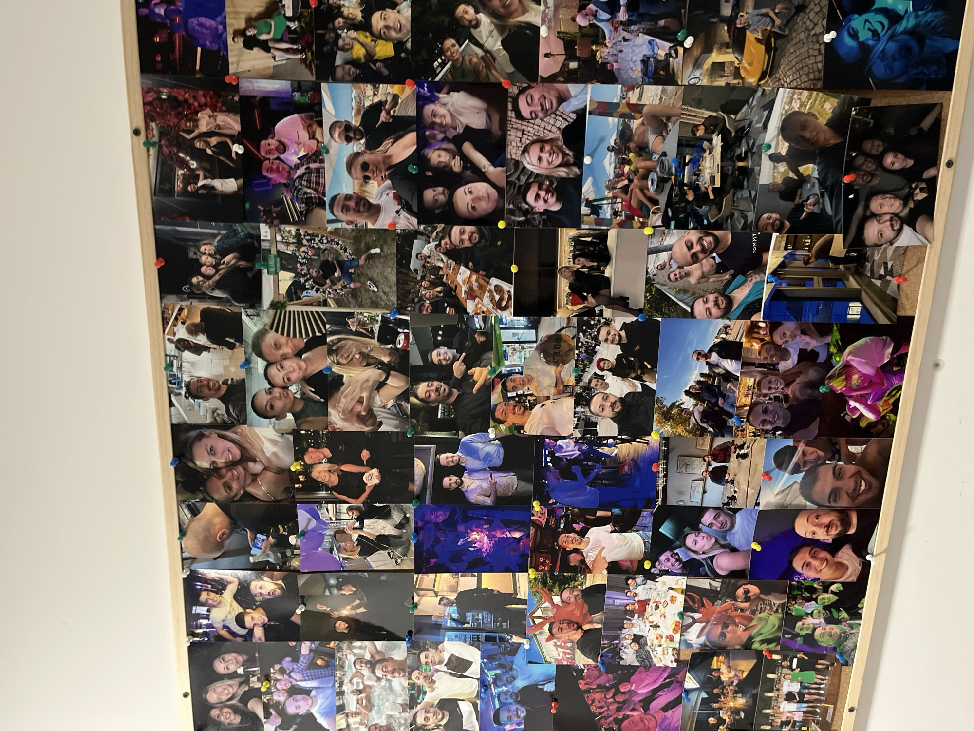 The media file presents a large collage of numerous printed photographs, meticulously arranged in a grid-like fashion on what appears to be a cork board or wooden display panel. Many of the individual pictures are secured with colorful pushpins, including red, yellow, blue, green, and white.
The primary subjects across the collage are young to middle-aged adults, almost universally depicted smiling, laughing, and interacting in groups or pairs. The overarching theme is one of social gatherings, celebrations, and shared joyous moments.
The photos capture a wide variety of settings and activities. Many images show people dining and drinking in restaurants and cafes, both indoors and outdoors. Lively bar and club scenes are prominent, characterized by darker lighting, vibrant neon glows, and celebratory atmospheres, suggesting parties and nightlife. Other settings include casual outdoor gatherings, possibly parks or cityscapes, and intimate home environments. There are also indications of travel or excursions in some backgrounds. Activities include sharing meals, toasting with drinks, dancing, posing for group photos and selfies, and general socializing. Some photos feature cakes and balloons, hinting at birthday celebrations or other special occasions.
The time of day varies significantly across the collage, ranging from bright daytime shots with clear skies to nighttime events illuminated by artificial lights. The emotions conveyed are overwhelmingly positive, reflecting happiness, friendship, and camaraderie among the individuals. Objects such as cocktails, beer glasses, food dishes, and decorative elements like balloons are frequently visible. In one specific image, a person is seen wearing a white t-shirt with "TOMMY" printed on it, and another wears a cap displaying "80S." The collage serves as a vibrant visual diary of cherished memories and lively social experiences, set within the context of Sofia, Bulgaria.