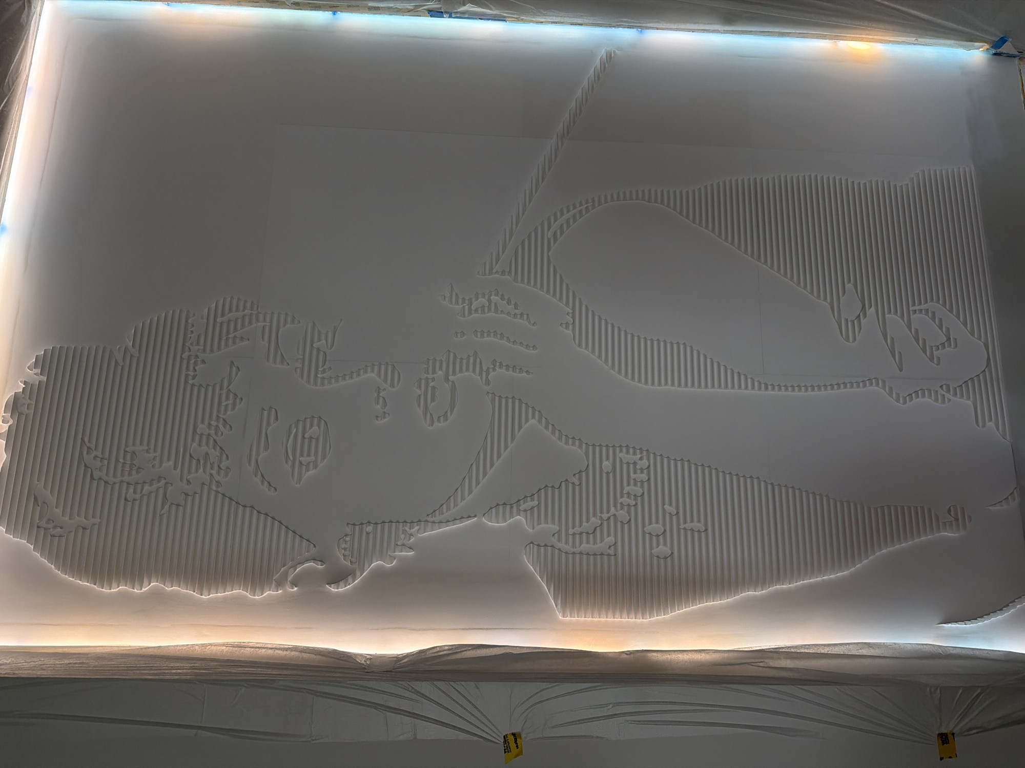A large, white, vertically striated depiction of a cartoon character resembling Betty Boop is illuminated from the top and bottom. The depiction is located inside a building covered in plastic tarps, likely in the city of Khimki, Russia.