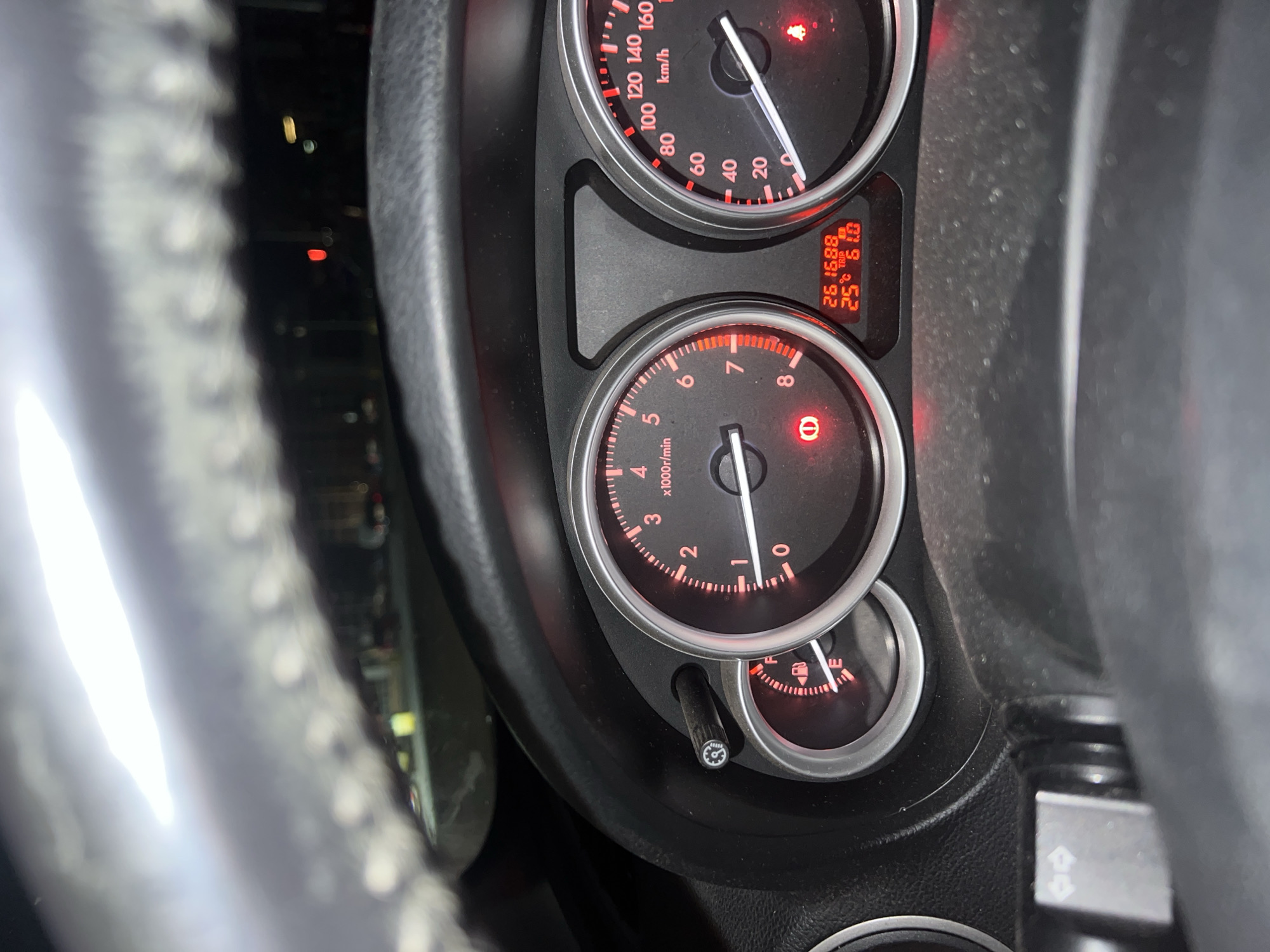 The image shows the dashboard of a car, most likely a Mazda based on the gauge layout, with the speedometer and tachometer illuminated in red. The speedometer needle is positioned at 0 km/h, and the tachometer needle is at 0 rpm. The odometer reads 261688 km, and the trip meter reads 61.0. The fuel gauge shows the tank is close to empty. The image does not contain any location or the location of Burgas, Bulgaria.