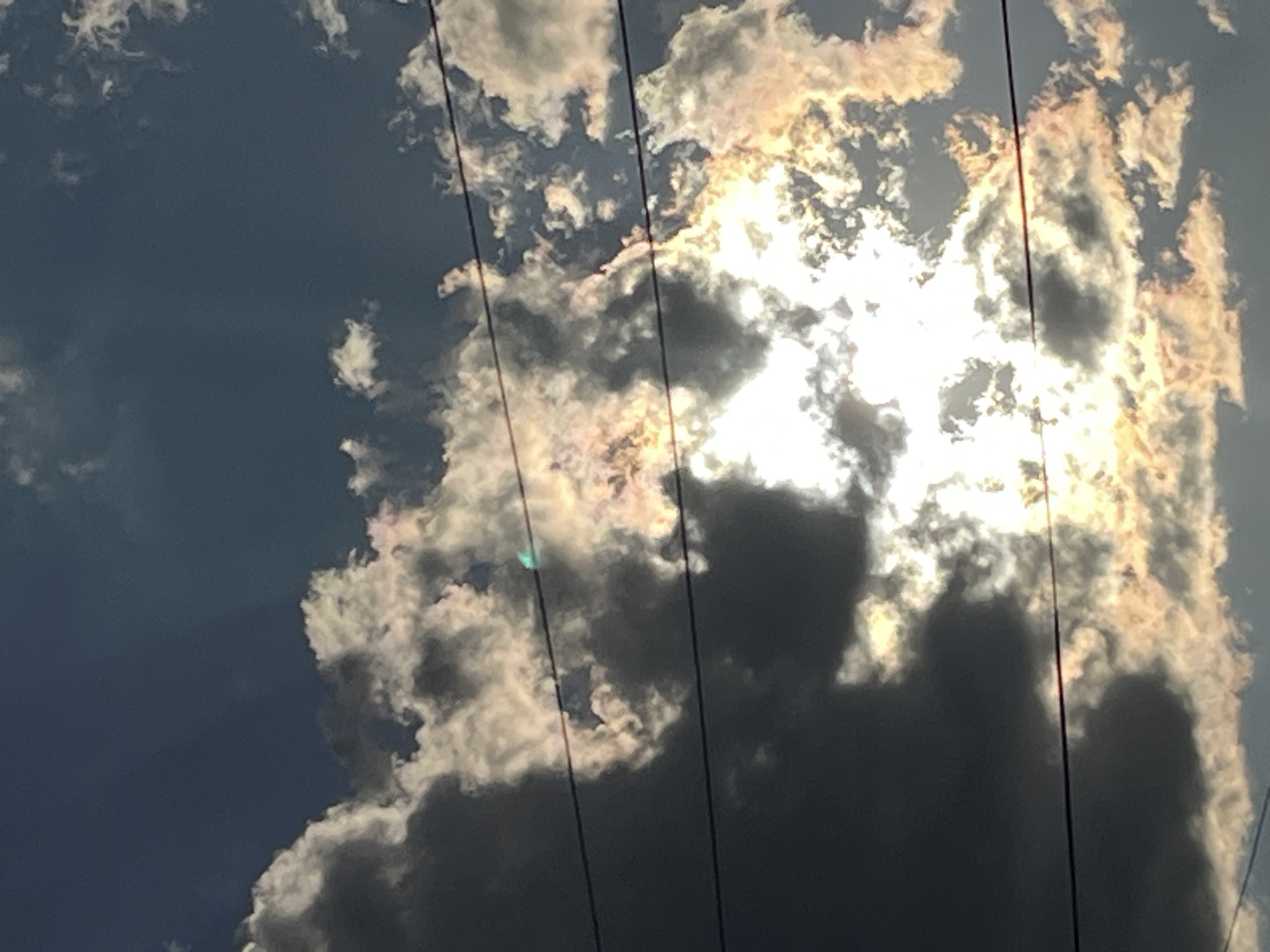 The image depicts a daytime sky with clouds partially obscuring the sun. Several electrical power lines intersect the scene. The location, Lozarevo, Bulgaria, cannot be determined from the visual data. There are no people depicted.