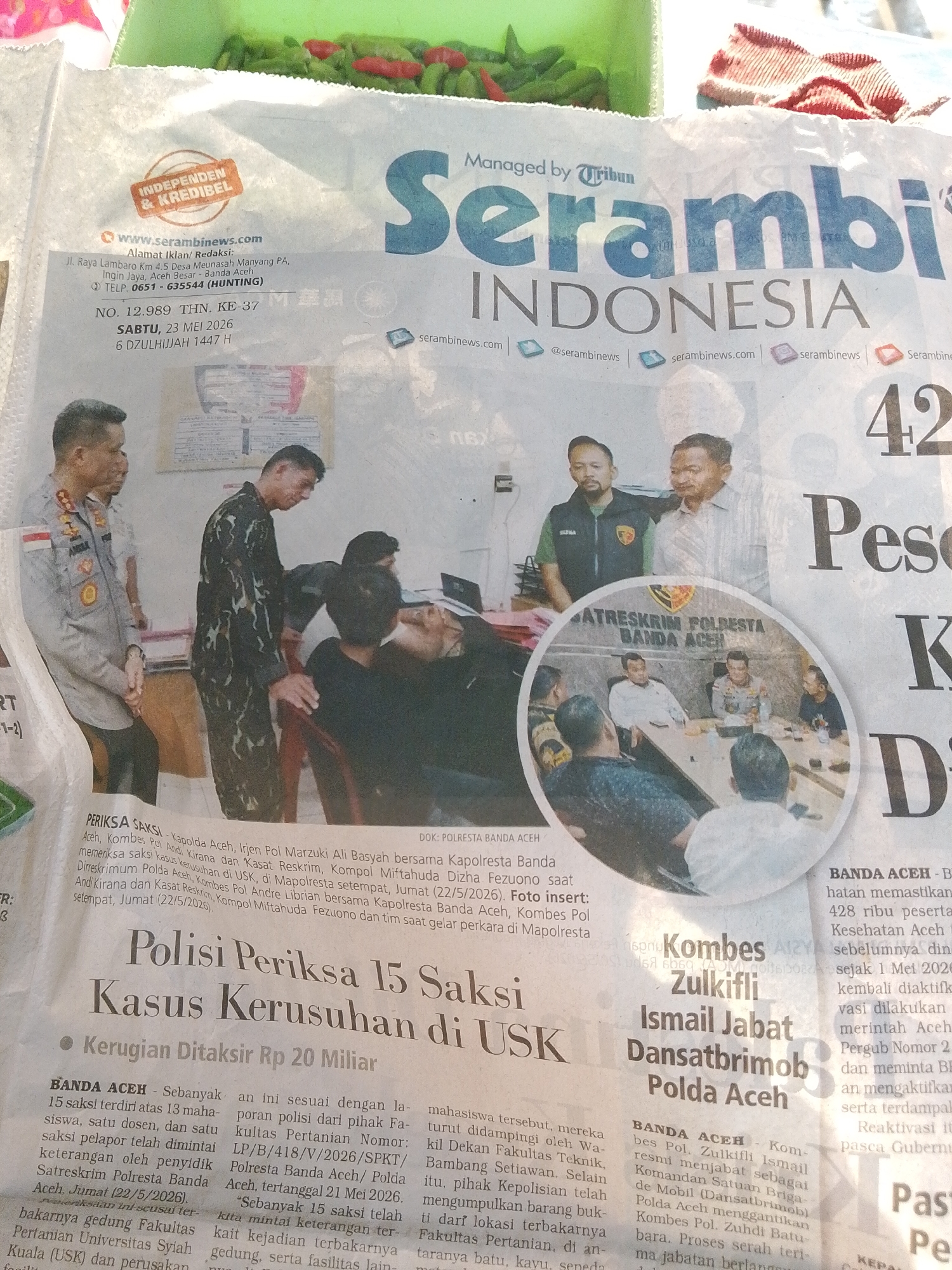 The image shows a newspaper article titled "Serambi INDONESIA." The article's headline reads, "Polisi Periksa 15 Saksi Kasus Kerusuhan di USK," which translates to "Police Examine 15 Witnesses in USK Riot Case." The article is dated Saturday, May 23, 2026, and refers to events occurring at Syiah Kuala University (USK). One part of the article mentions Polresta Banda Aceh. The newspaper includes images of police examining witnesses.