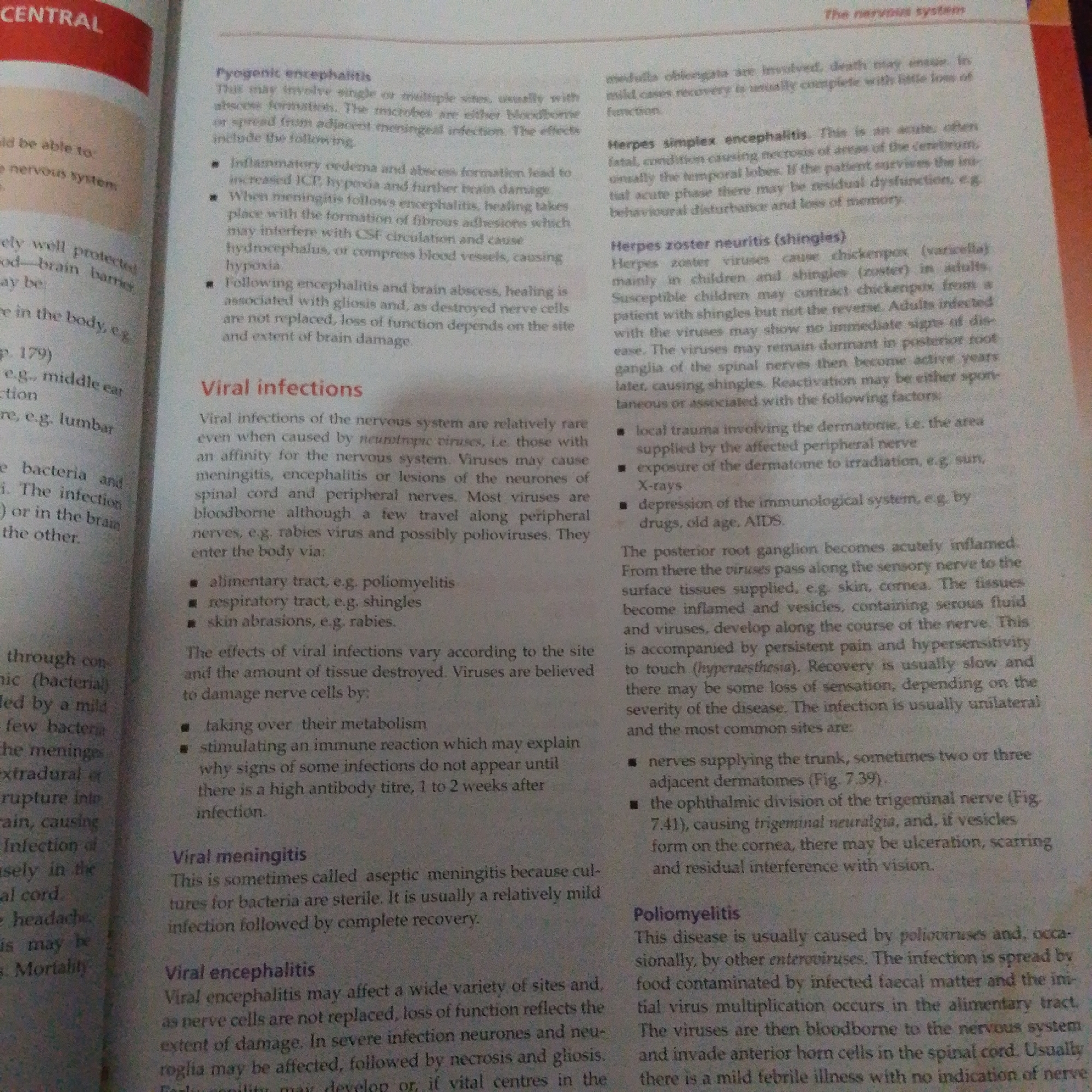 This is a close-up, slightly angled photograph of an open book. The page is filled with dense text, suggesting an academic or informational context. The text discusses medical conditions related to the nervous system, including "Pyogenic encephalitis," "Viral infections," "Herpes simplex encephalitis," "Herpes zoster neuritis (shingles)," and "Poliomyelitis." The layout indicates a textbook or reference material. The lighting is somewhat dim, and the image appears to be taken indoors, possibly in a study or library. The page itself is cream-colored and shows some signs of wear, common for a well-used book. There are no people or objects other than the book visible in the frame. The text is predominantly black ink. The overall impression is one of focused study or research.