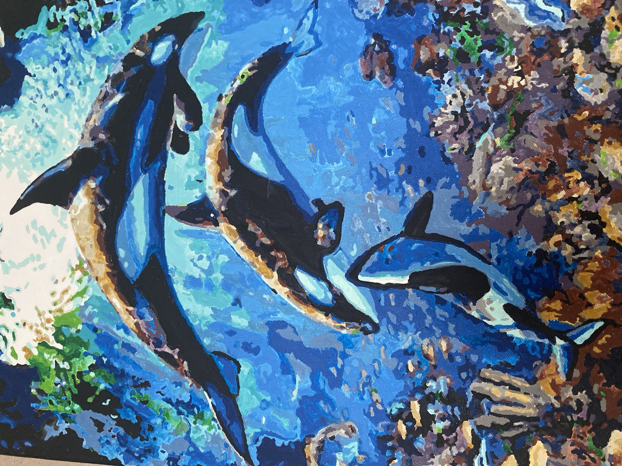 The image is a painting of three orcas swimming in a blue ocean. The orcas are depicted in black and white with some brown markings. The ocean is a vibrant blue, with lighter and darker shades indicating depth and light. There are also some coral reefs and small fish visible in the background, rendered in a variety of colors. The painting style is somewhat abstract, with visible brushstrokes and a textured appearance. There is no indication in the image or the provided crops that this scene is located in Vvedenka, Ukraine.
