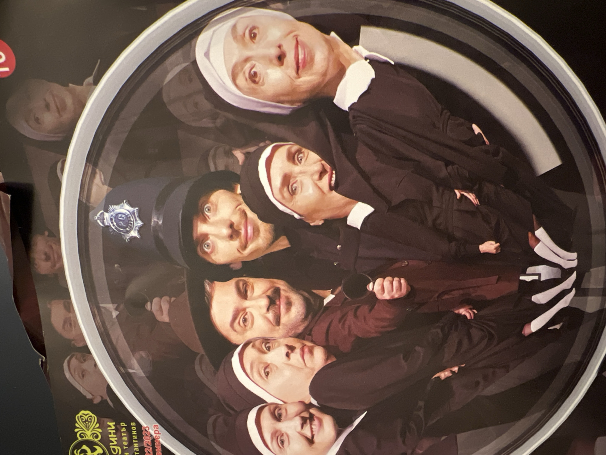 A round poster depicts a group of five people in a circular arrangement. Four of them are dressed as nuns in black habits with white head coverings. One person in the group is wearing a dark blue police hat. A fifth person is wearing a brown shirt and holding a black cup. The poster is advertising an event at the Konstantin Kisimov Theater in Sofia, Bulgaria.