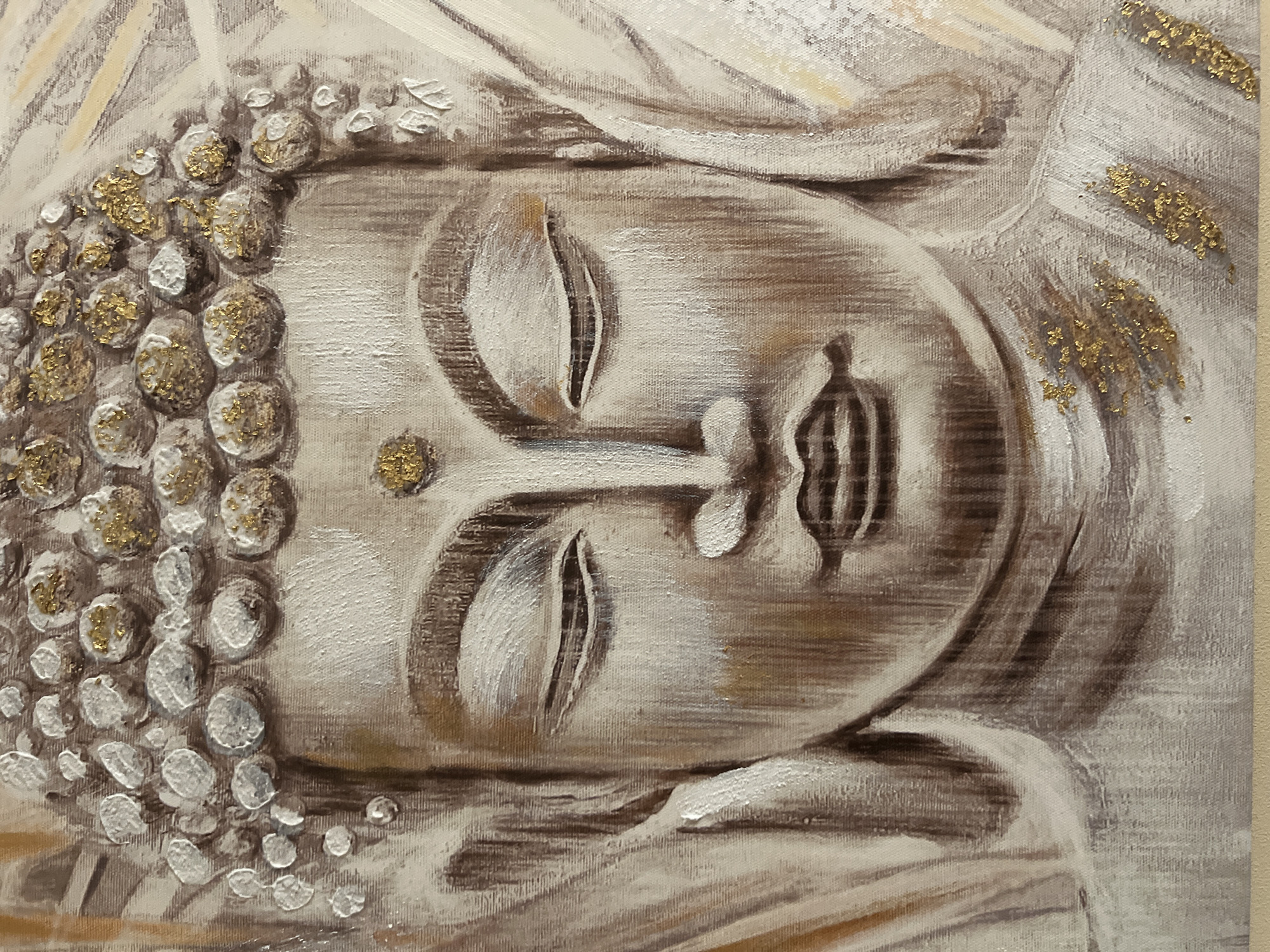 This is a close-up, horizontal, textured painting of a serene Buddha face. The artwork is rendered in muted tones of beige, brown, and white, with accents of gold leaf. The Buddha's eyes are closed, conveying a sense of deep meditation and tranquility. His hair is depicted as a series of rounded, textured curls, many of which are highlighted with gold leaf, giving them a jewel-like appearance. The facial features, including the nose and lips, are subtly defined with shading.
The background of the painting features abstract, flowing lines in shades of white and beige, suggesting drapery or light rays. Scattered gold leaf accents are also visible in the background, adding to the ethereal and spiritual quality of the artwork. The texture of the canvas is apparent, indicating it is likely an oil or acrylic painting with impasto techniques used to create depth and dimension. The overall impression is one of peaceful contemplation and spiritual enlightenment. There is no visible text in the image. The context of Minsk, Belarus, is external information and does not directly influence the visual description of the artwork itself.