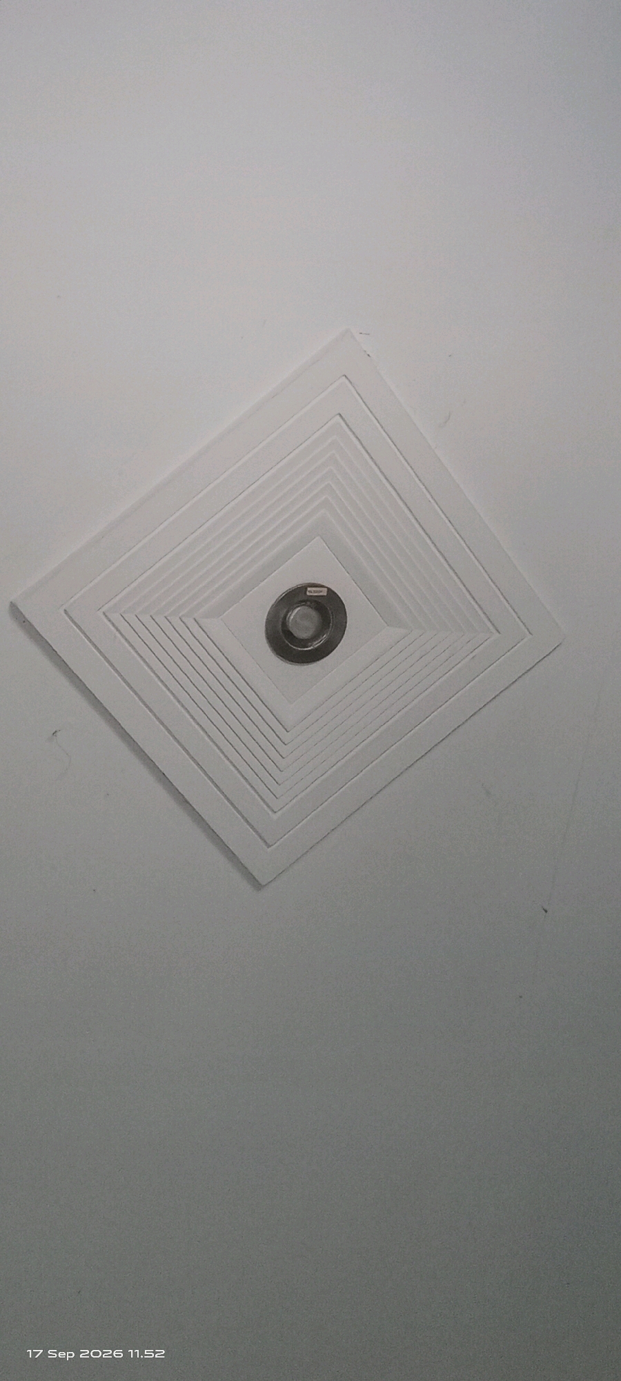 The image shows a square recessed ceiling vent with a concentric diamond pattern. A small circular light fixture is centered within the vent. The ceiling is painted white and appears to be flat. A timestamp in the lower-left corner reads "17 Sep 2026 11.52". There are no people or other objects visible in the frame. This appears to be an interior photograph of a ceiling, possibly in a residential or commercial building. The specific location in Klaten, Indonesia is not ascertainable from the image itself.