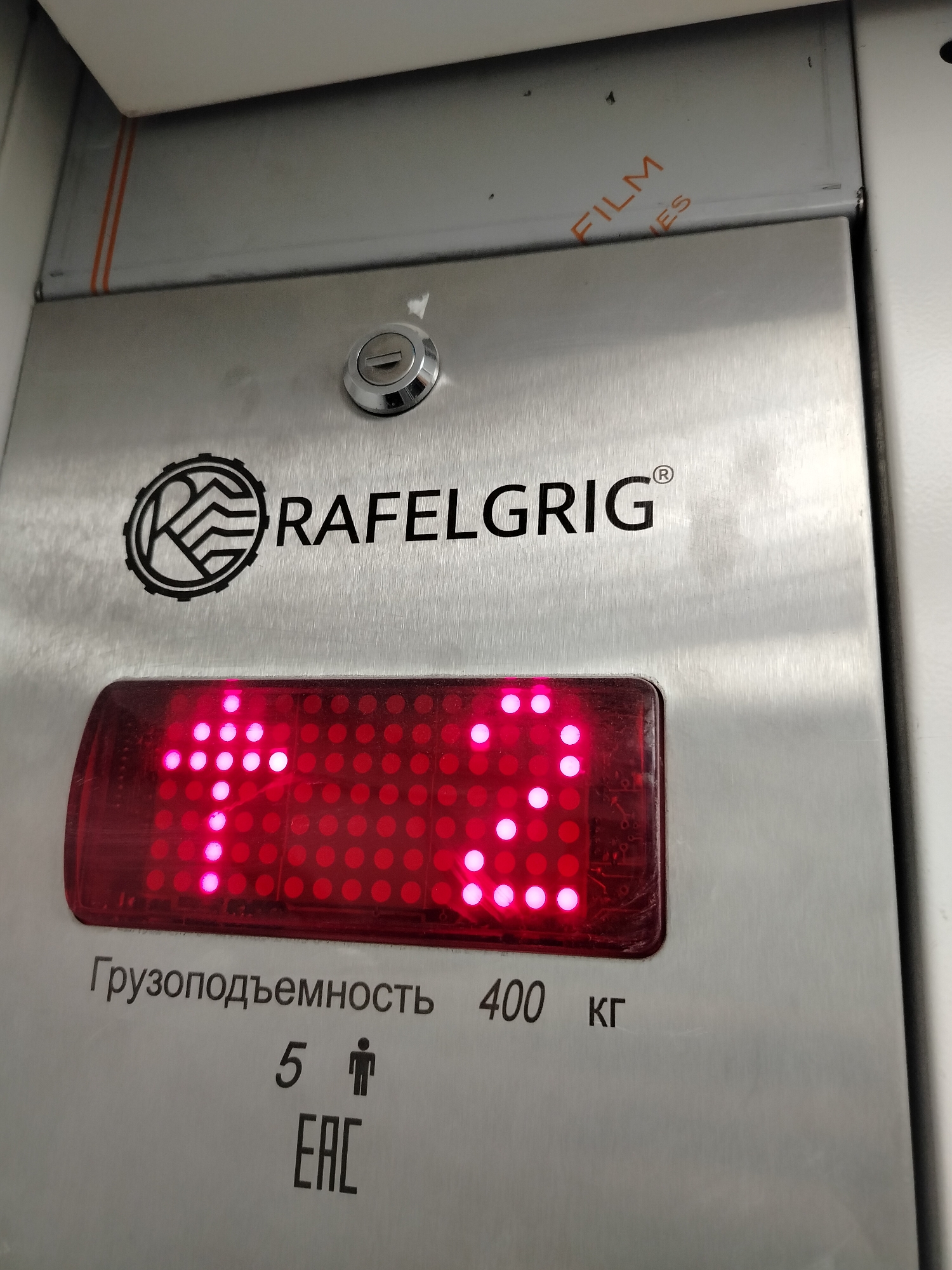 The image shows a close-up of an elevator panel. The panel is metal and features the "RAFELGRIG" logo. Below the logo is a red digital display that reads "13". Under the display, there is an inscription in Russian, "Грузоподъемность 400 кг," which translates to "Load capacity 400 kg." There is also a symbol of a person standing with the number 5, indicating a maximum of 5 people. The image also features an "EAC" mark. A small keyhole is positioned above the logo. The location is Yerevan, Armenia.