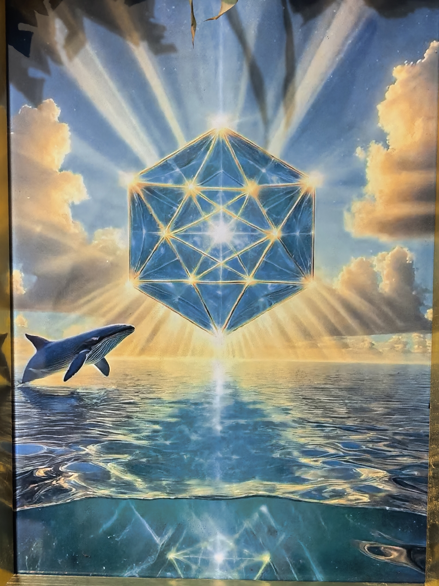 The image depicts a surreal scene over the ocean. In the sky is a geometrically complex, glowing blue structure with golden lines. Light rays emanate from it. Below, a whale leaps out of the water. The water is rendered in detail, showing the surface and the underwater portion, with light reflecting off the ocean floor. Clouds are visible in the sky with golden light shining between them. Location: Unknown, Unknown.
