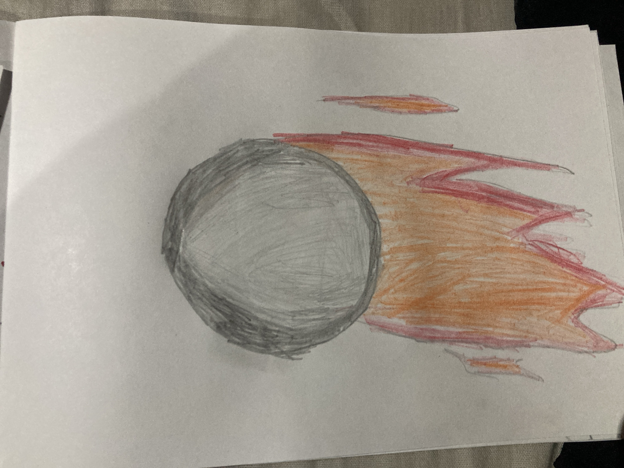 This is a drawing on white paper. A large gray circle, presumably a moon or planet, is depicted at the top of the drawing. Below the circle, orange and red lines are drawn to represent flames or exhaust. There are two smaller, separate flame shapes to the right of the main flames. The drawing appears to be done with colored pencils. The location in the city of Besedy, Russia is not discernible from the image.