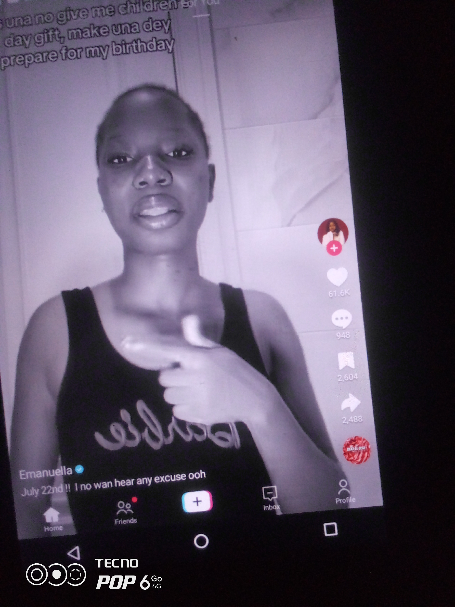 The image shows a young Black woman in a dark tank top speaking into a phone camera. The text overlay at the top of the screen reads, "s una no give me children for you day gift, make una dey prepare for my birthday". The woman is gesturing with her right hand, pointing towards herself. On the right side of the screen, there are icons for likes, comments, shares, and a profile picture. The bottom of the screen displays navigation icons for Home, Friends, Inbox, and Profile, along with the TECNO POP 6 4G logo. The image appears to be a screenshot from a social media video, likely recorded indoors. There is no discernible information in the image that would indicate the location is Howayi, Nigeria.