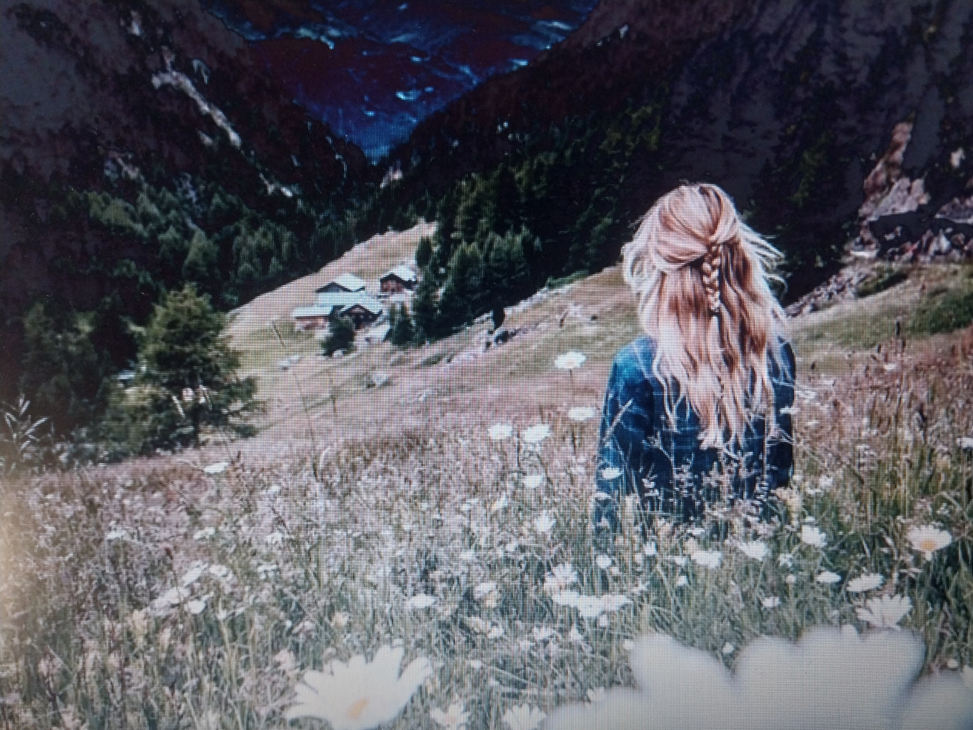 An outdoor, wide shot captures a young woman with blonde hair braided into a single braid down her back, facing away from the camera. She is in a meadow filled with white wildflowers and green grass. She is wearing a dark blue denim jacket. Behind her, the landscape slopes upwards, covered with trees. In the distance, nestled in the trees on the hillside, are several wooden buildings with dark roofs, suggesting a small village or settlement. The background features a dark, rugged mountain range under a deep blue sky. The overall scene conveys a serene and natural setting. The location is Unknown, Unknown.
