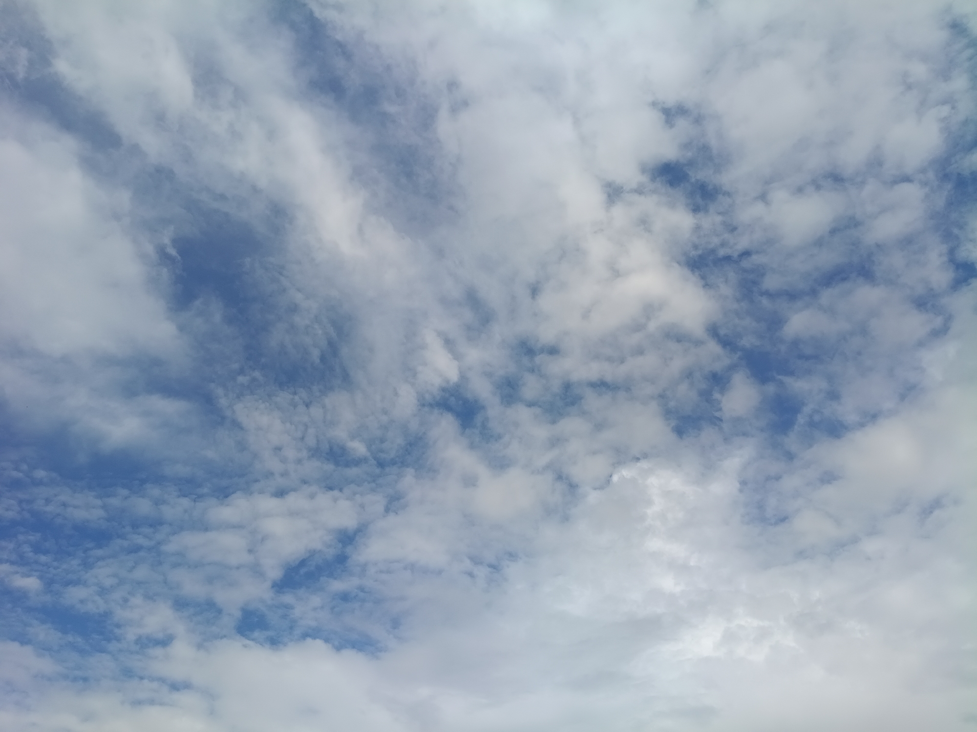 The image shows a sky with scattered clouds, predominantly white and fluffy, against a backdrop of blue. There are no people, subjects, objects, or actions visible in the image. The environment depicted is an outdoor sky with natural cloud formations. No specific location in the city of Litynia, Ukraine, can be determined from this image.