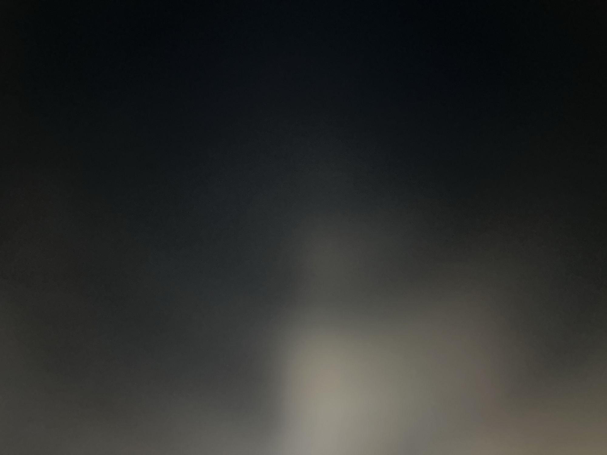 The image depicts a dark, abstract background with a subtle gradient from a lighter, muted tone on the left to a deep black on the right. There are no discernible subjects, objects, people, or actions present. The scene appears to be indoors or in a controlled environment due to the lack of natural light and context. The image is highly underexposed and out of focus, making it impossible to identify any specific features or provide a location within Belgrade, Serbia, or any other city.