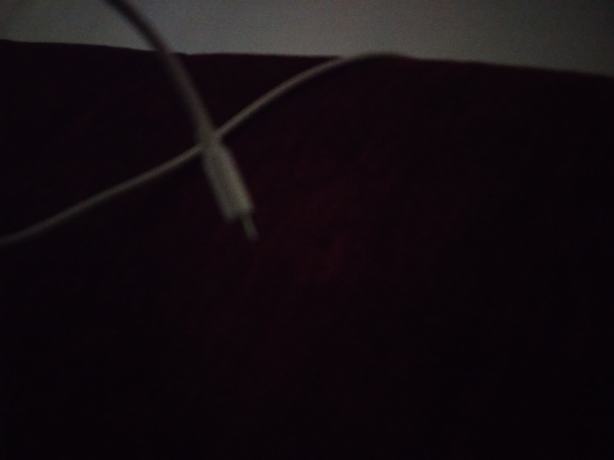 The image shows a white USB cable lying on a dark surface, potentially a piece of furniture. Due to the lack of contextual details and identifiable landmarks in the image, it's impossible to determine if the photo was taken in Yerevan, Armenia, or anywhere else.