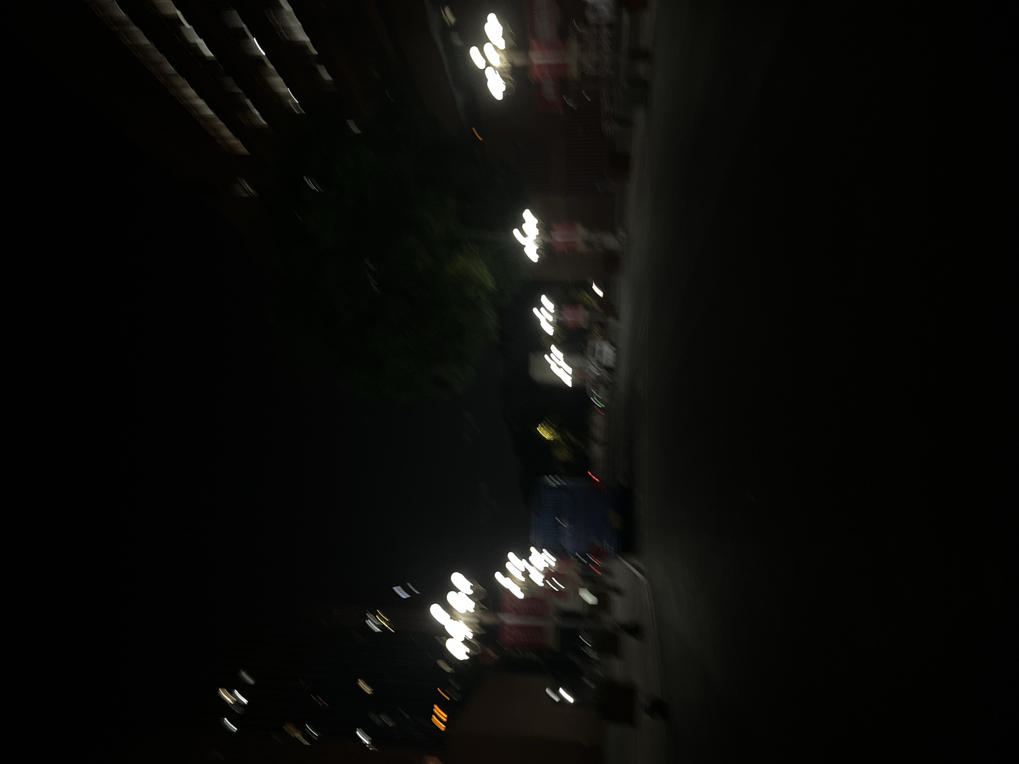 The image appears to be taken at night in an urban environment. Several rows of streetlights illuminate what seems to be a street and nearby buildings. The lights are somewhat blurred, suggesting movement during the photo capture. Structures are visible along the street. The overall scene suggests a street view in a city. Although a specific location in the Yuzhong District cannot be determined.