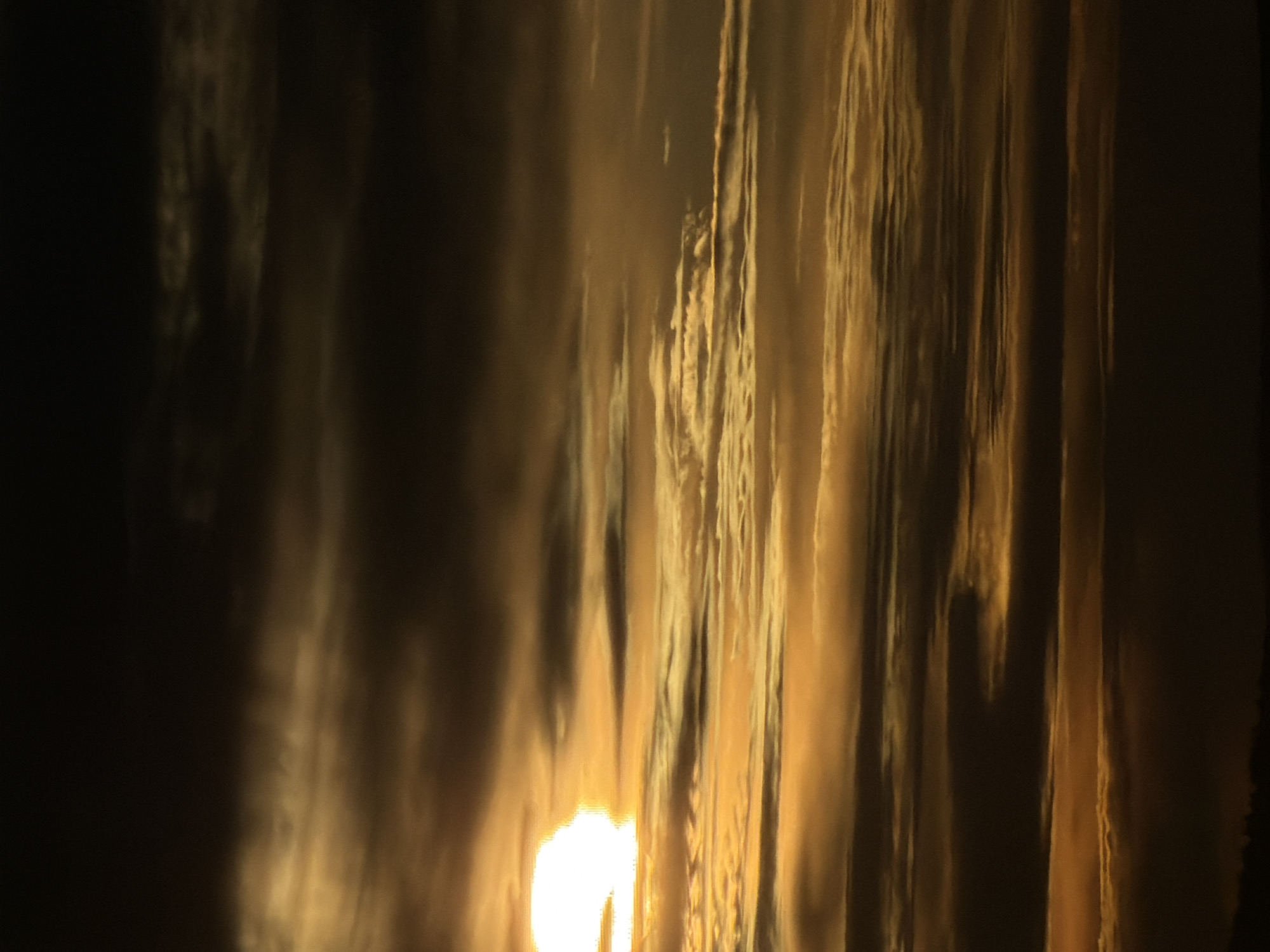 The image shows a body of water reflecting sunlight, possibly at sunset or sunrise. The reflection is distorted, creating vertical streaks of light and shadow. The exact location in Krasnoyarsk, Russia cannot be determined from the image alone.