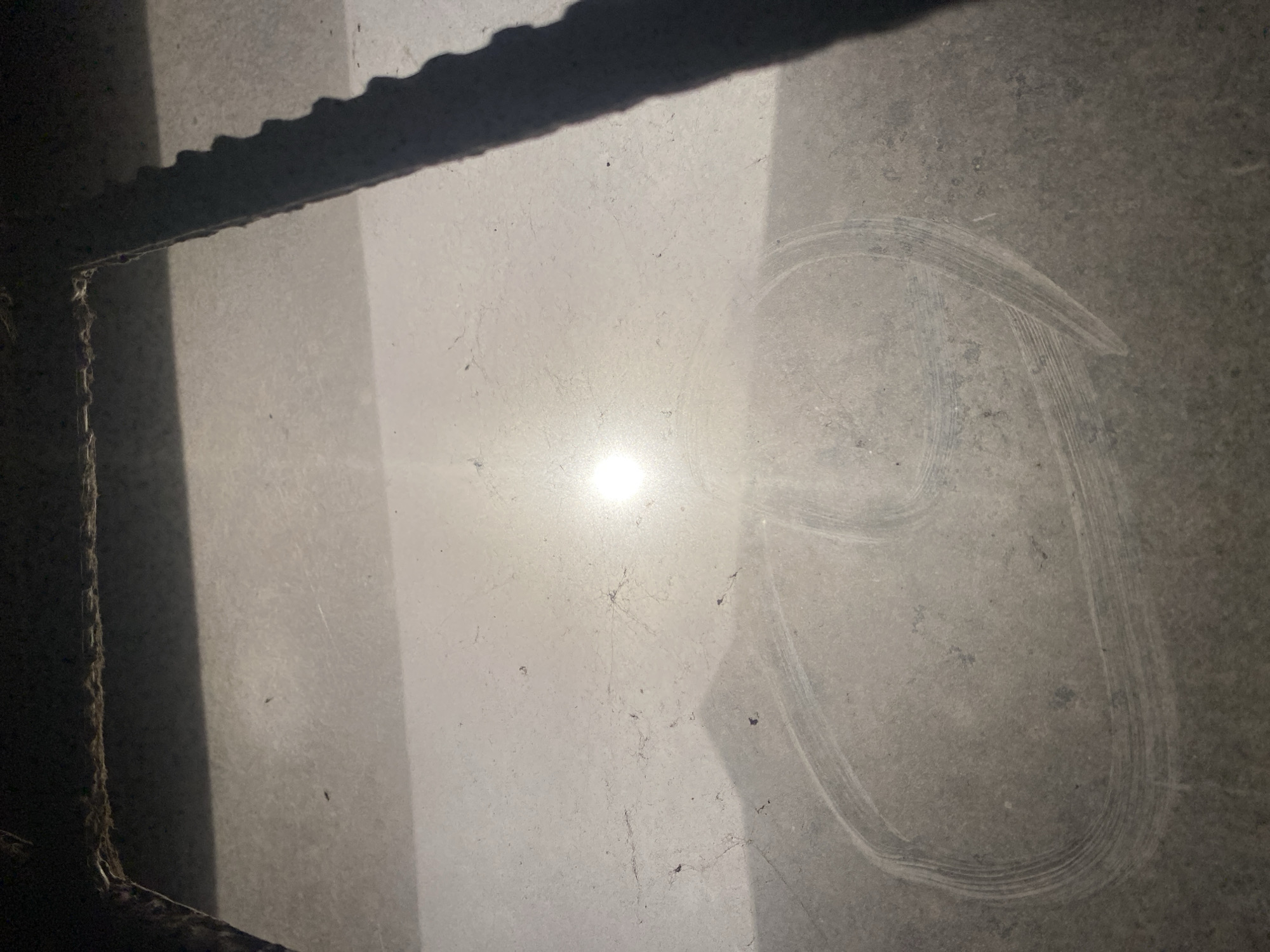 The image shows a section of a window with significant dust and grime. A bright light source is visible through the window, possibly sunlight. There are markings or smudges on the glass in the shape of a partial circle, appearing to have been made by wiping or rubbing. The top of the window frame is partially visible at the top of the image. The image appears to be taken indoors.
There is no information indicating that the image was taken in Ikorodu, Nigeria.