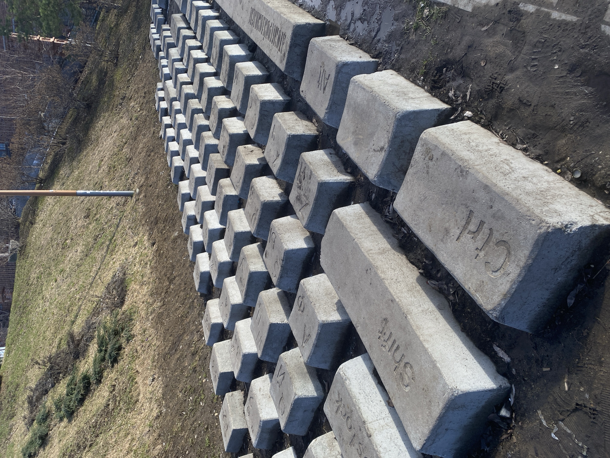 The image shows a long row of concrete blocks resembling a keyboard lining a grassy area and a patch of bare earth. The blocks are arranged to mimic a keyboard layout, with letters and symbols etched into the top surface. The words "Ctrl," "Shift," and "Alt" are visible. The location is identified as Yekaterinburg, Russia. A metal pole is partially visible near the grassy area. The environment appears to be outdoors on a sunny day.