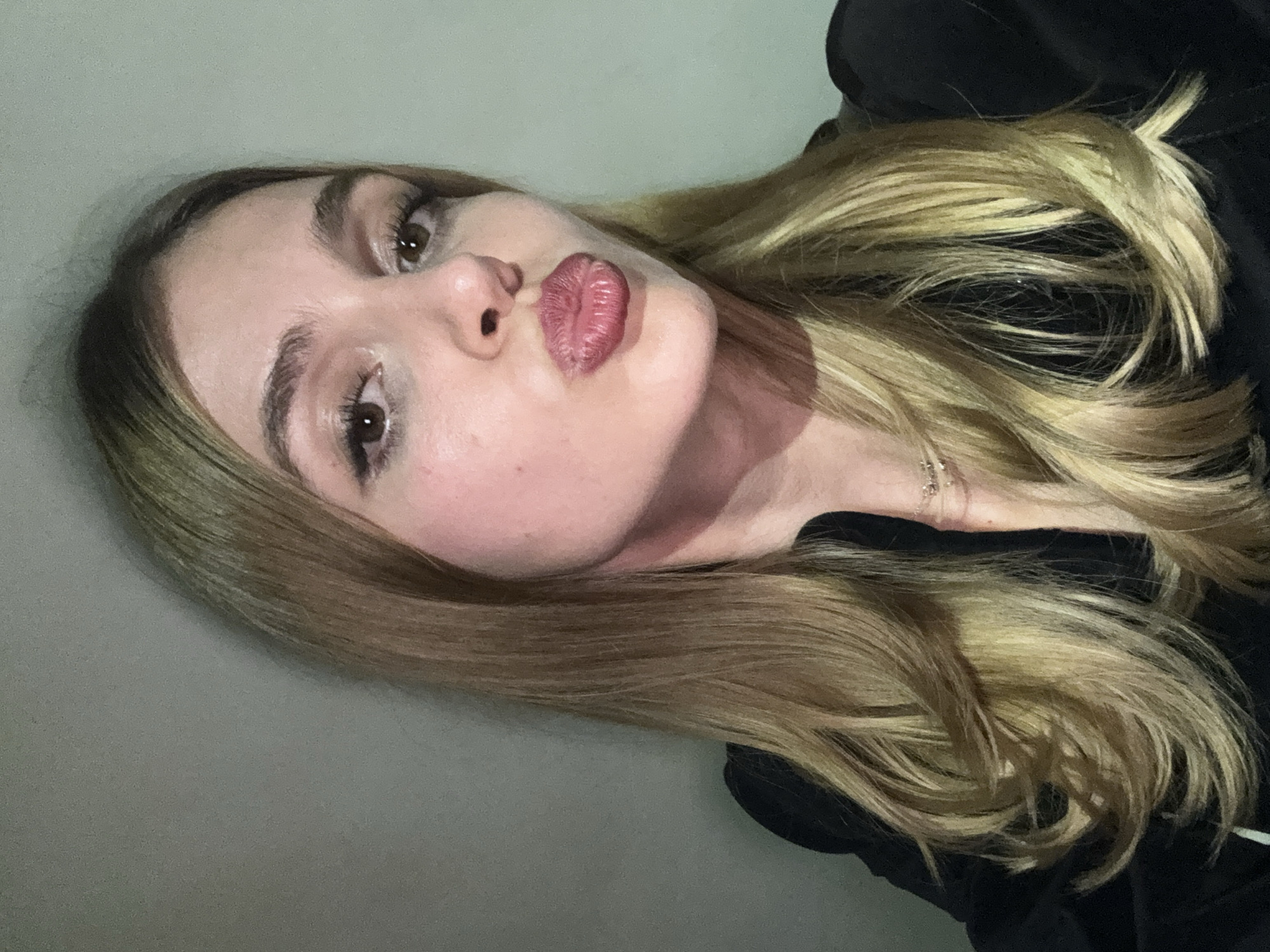 A young woman with blonde hair is looking at the camera with a pout. She appears to be in an indoor environment with neutral-colored walls. There are no contextual clues to indicate a specific location like Parakar, Armenia.
