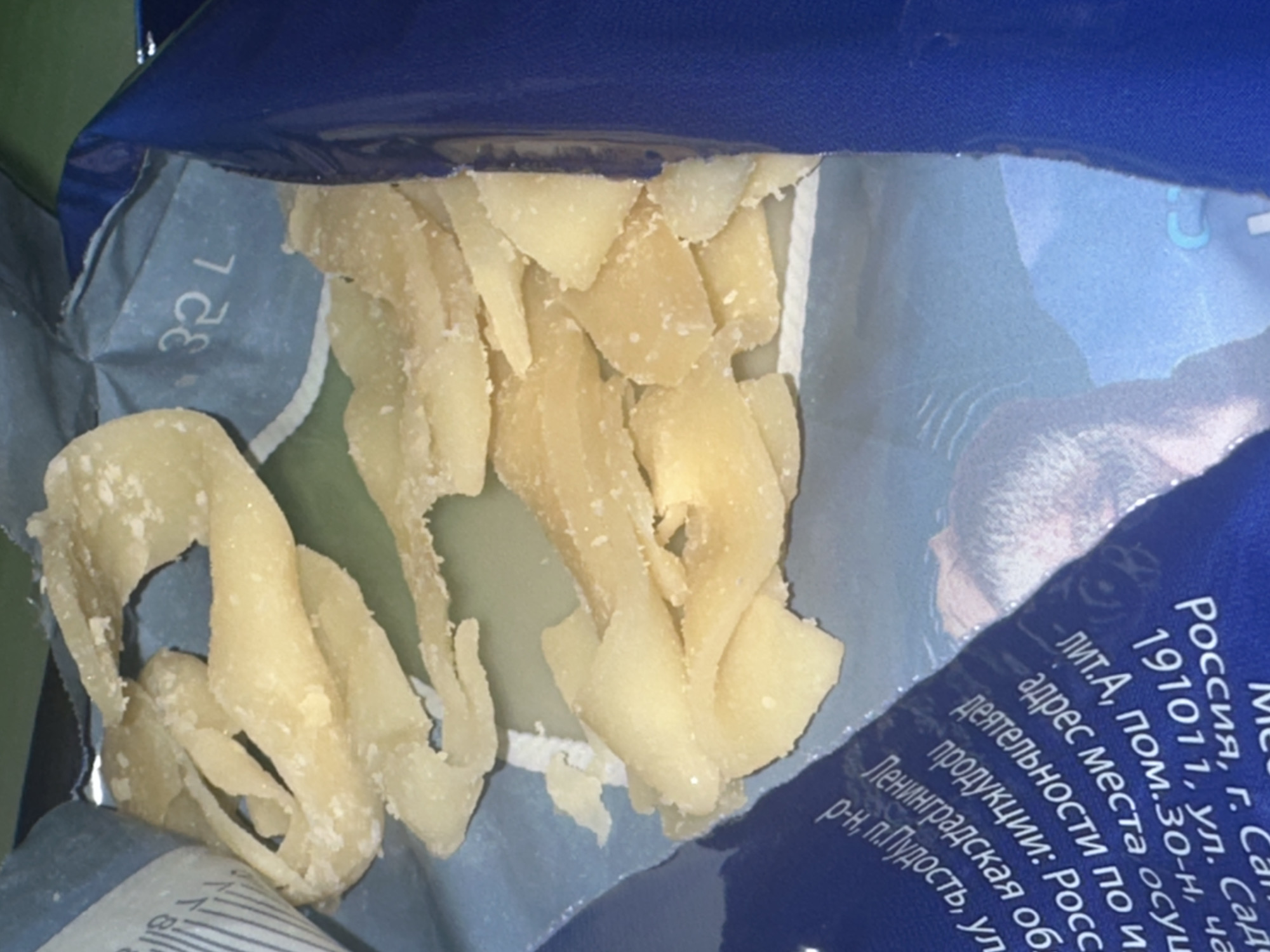 The image shows an open package of what appears to be dried and candied fruit, possibly ginger or another similar product. The packaging is blue and contains Russian text identifying the location as Moscow, Russia, specifically 191011, Sadovaya Street, including a partial address. There is also an image of a person in the background of the label.