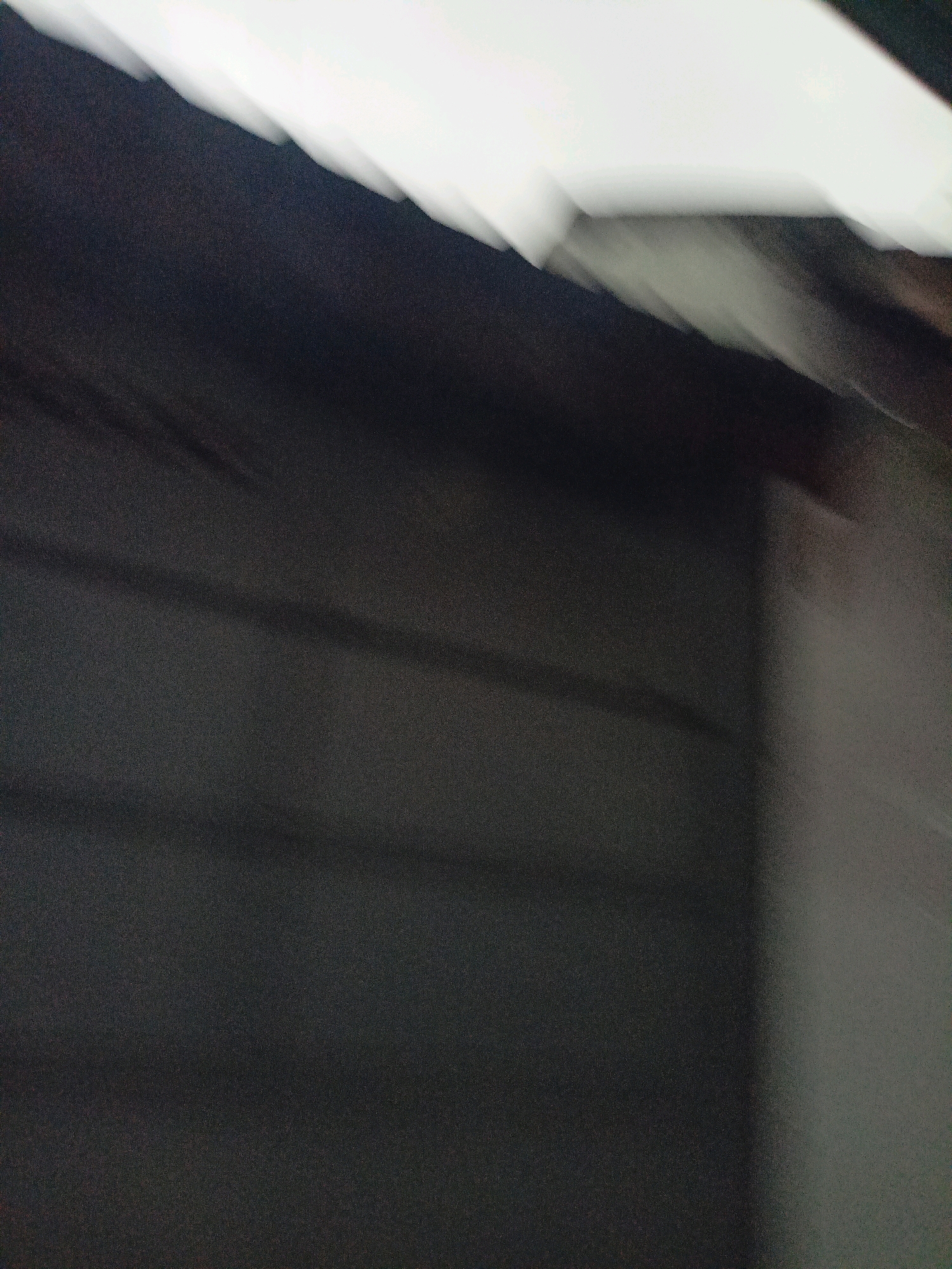 The image shows a dark, abstract scene with a blurry, horizontal line of bright white at the top. The overall impression is one of movement or a lack of focus. There are no discernible people, objects, or specific actions visible. The environment is underexposed and lacks clear features, making it impossible to determine a specific location, let alone within the city of Payaman, Indonesia. The texture of the surface appears rough and granular.