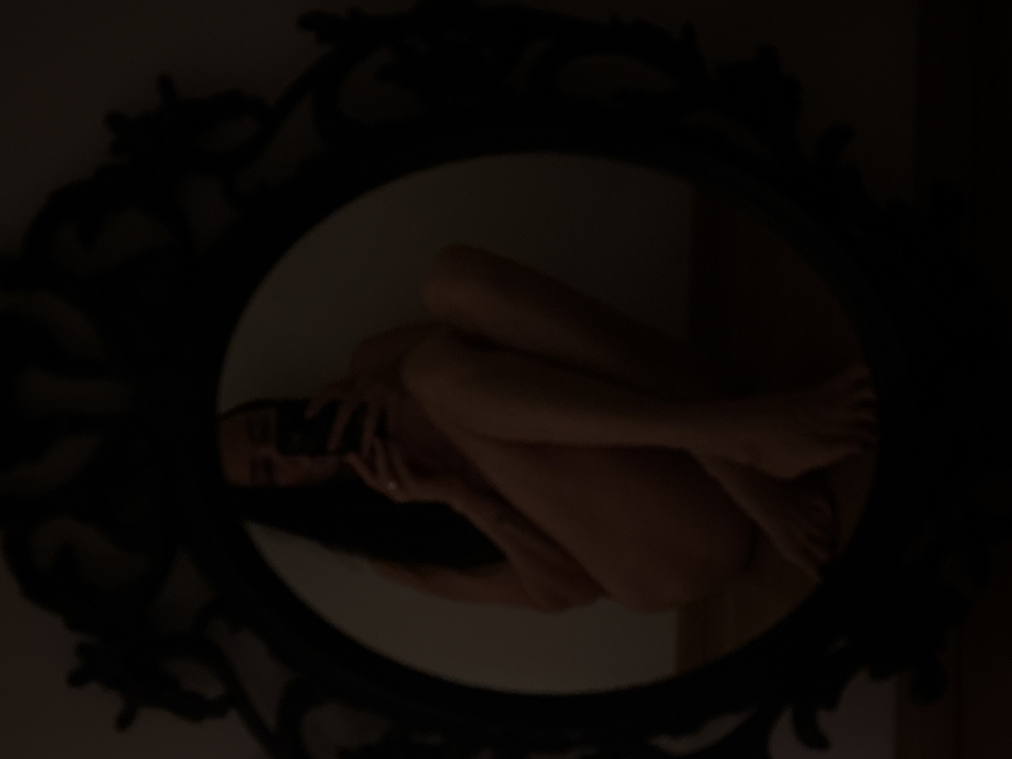 A mirror with an ornate, dark-colored frame reflects a nude woman curled into a fetal position. The location is not discernible from the image, and therefore, it is impossible to confirm if it is in Chaikovsky, Russia.
