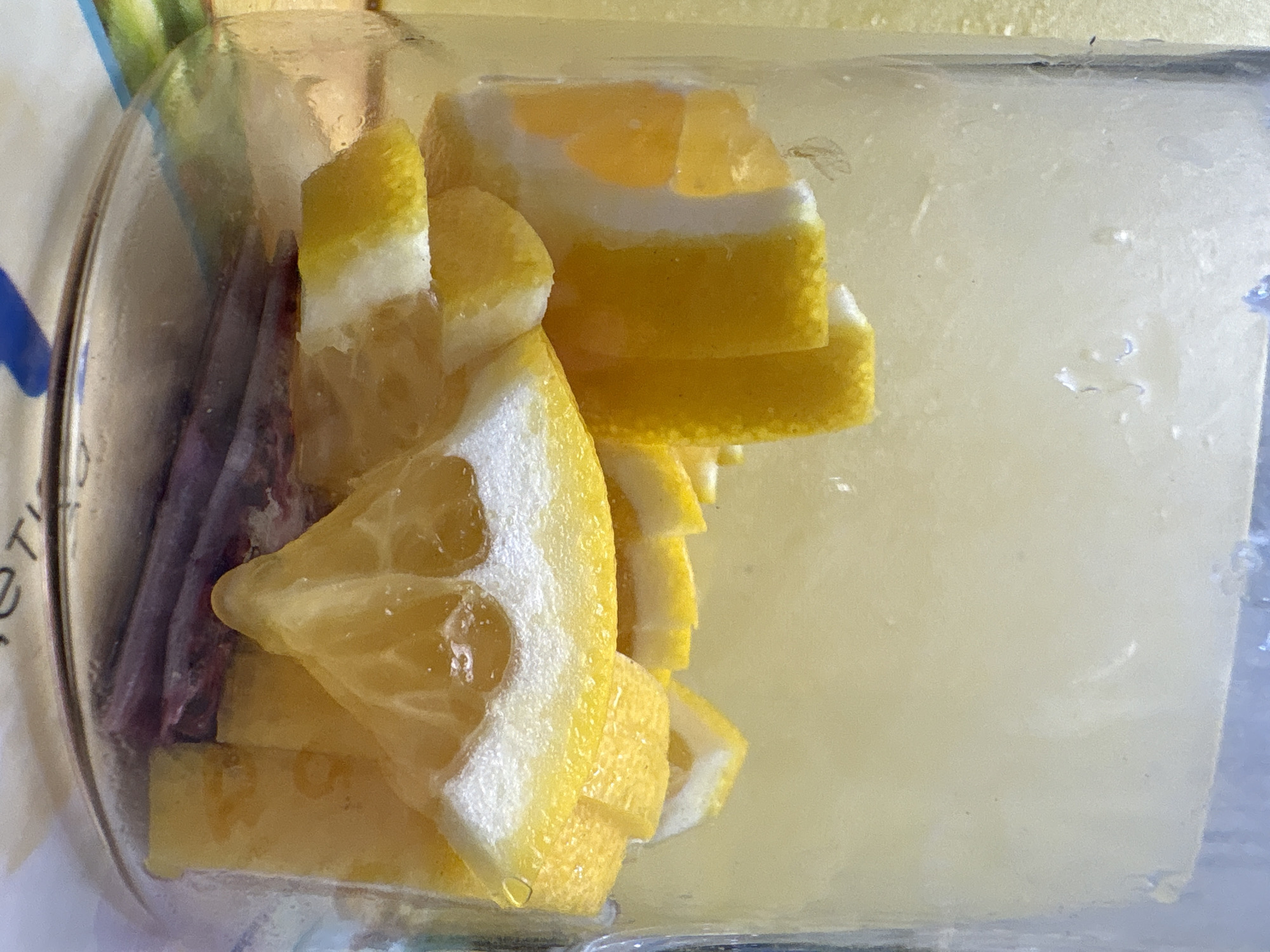 The image shows a close-up view of sliced lemons inside a glass jar. The lemons are cut into wedges and appear to be submerged in a light-colored liquid, possibly water or juice. The jar is transparent, allowing the viewer to see the contents clearly. Some of the lemon slices have a white pith layer visible, and the flesh is bright yellow. The background is softly blurred, suggesting the jar is on a surface. There is no indication of any specific location in the city of Засечное, Russia, or any people or actions depicted.